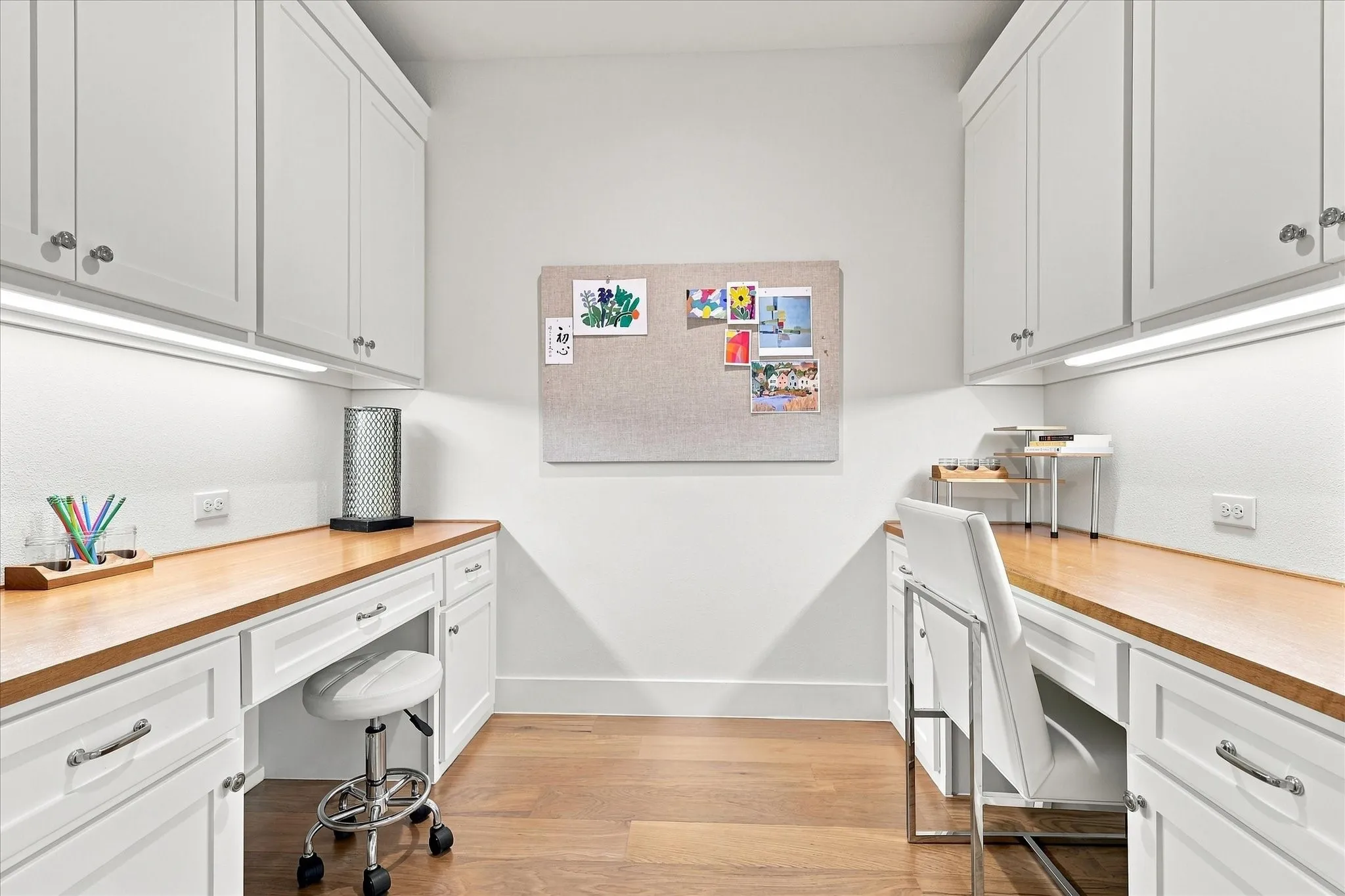 Dual built-in workspaces featuring wood-finish countertops, white cabinetry with silver-tone hardware, and integrated under-cabinet lighting