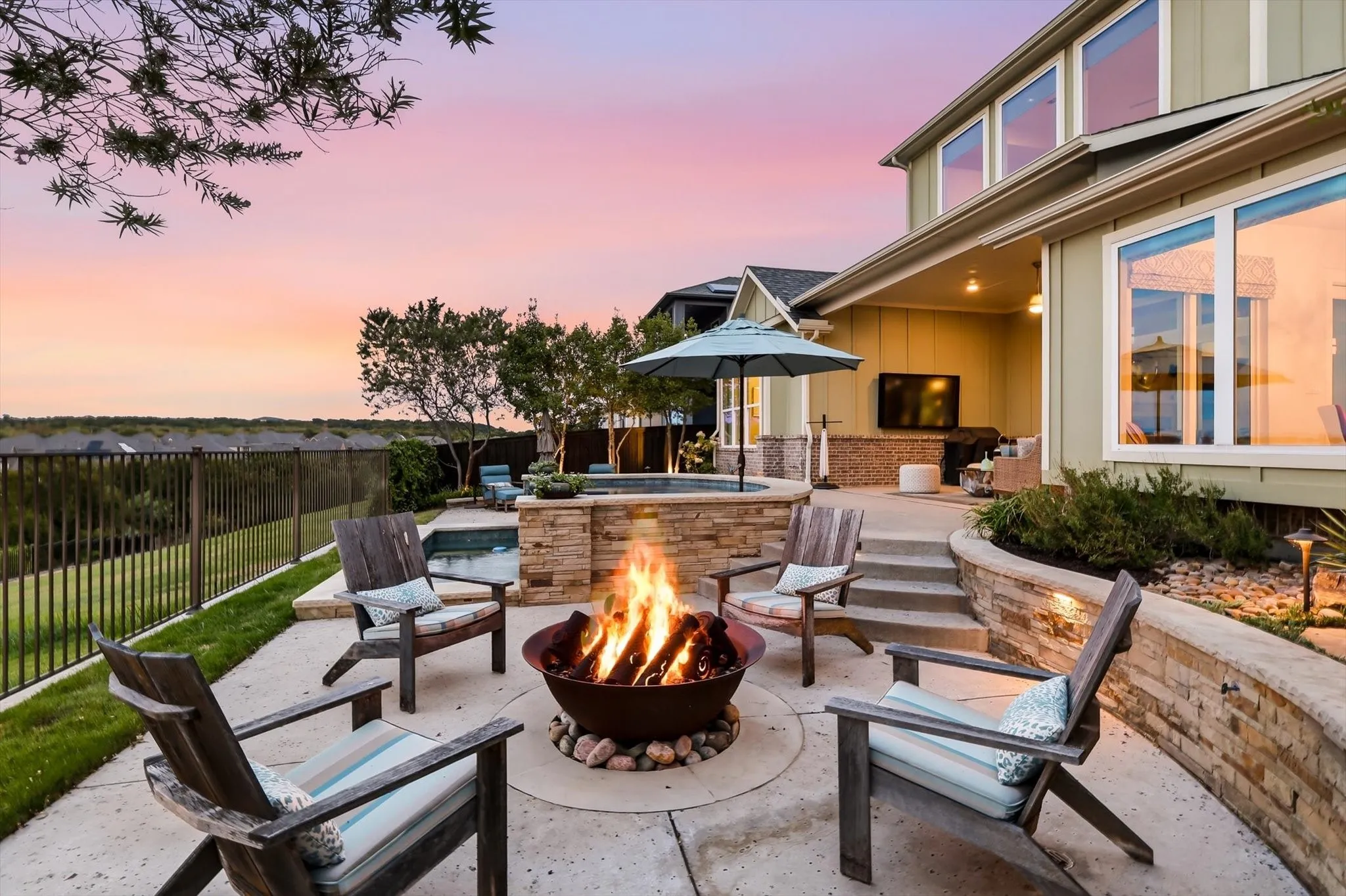 Expansive outdoor patio with a built-in fire pit, stone-stacked retaining walls, and tiered landscaping