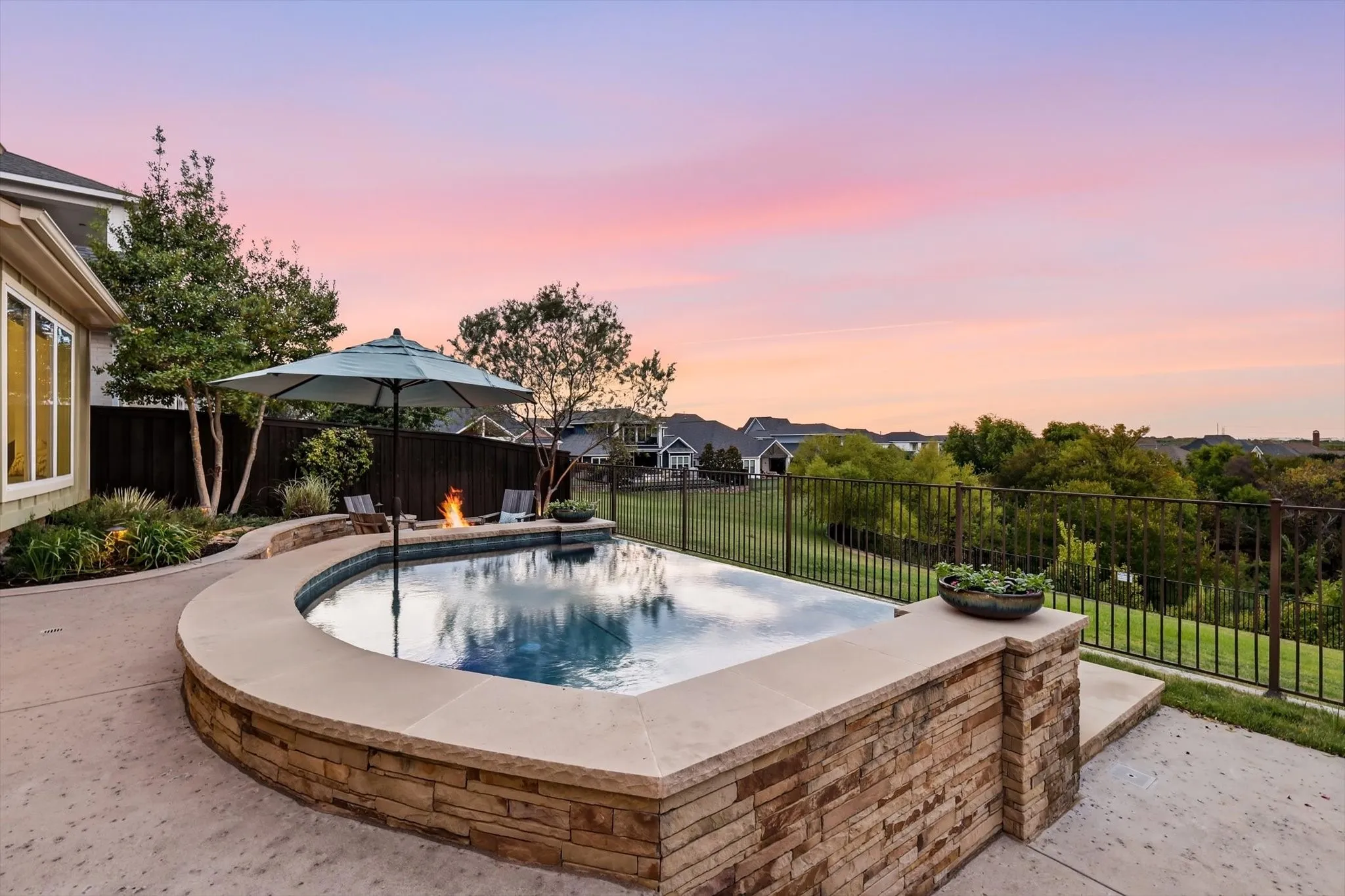 Curved stone-clad pool with an integrated fire pit