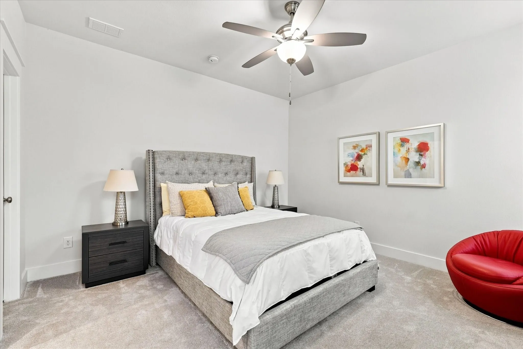 Plush carpet flooring, neutral paint palette, ceiling fan with light fixture, and two-drawer nightstands