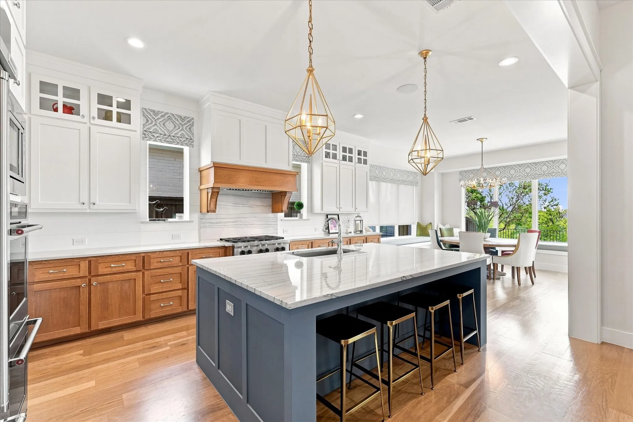 Kitchen featuring a large island with stone countertop, stainless steel appliances, wood-finish flooring, and pendant lighting
