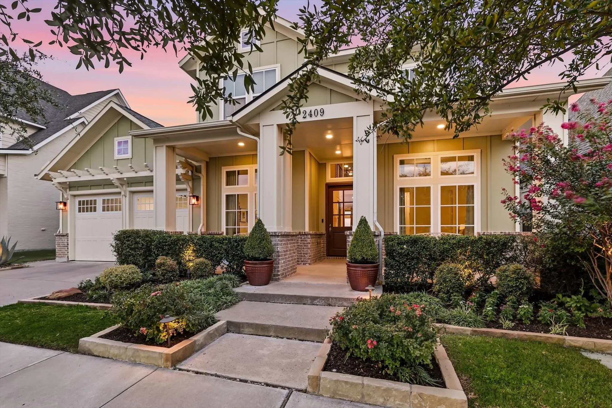 Two-story residence featuring a covered front porch, brick detailing, and an attached two-car garage