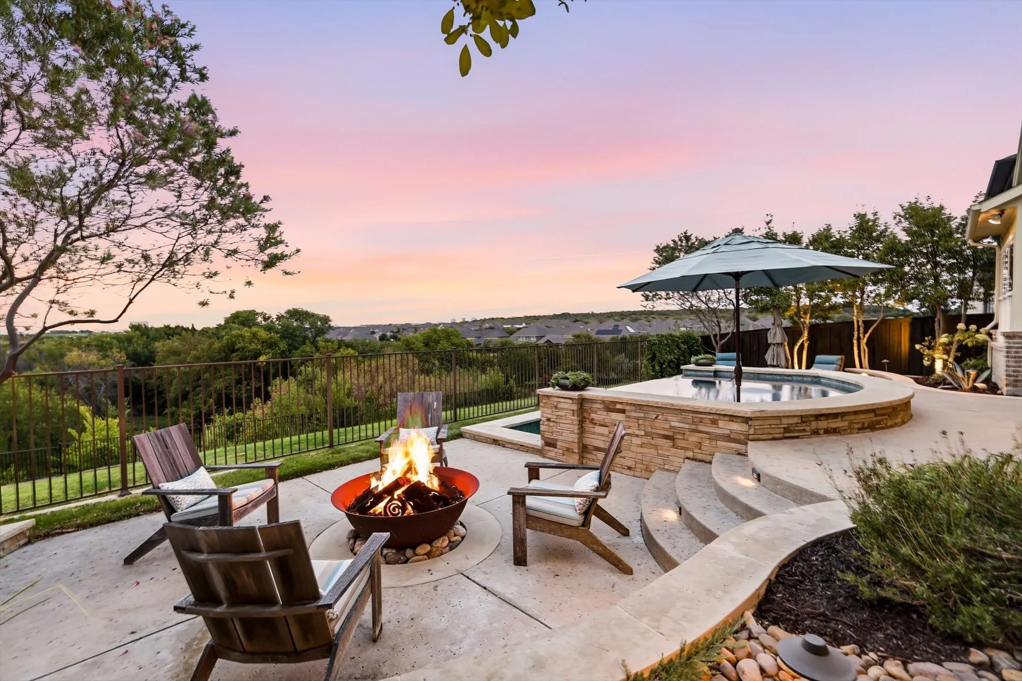 Expansive patio featuring a fire pit, built-in spa with stone surround, and terraced concrete steps