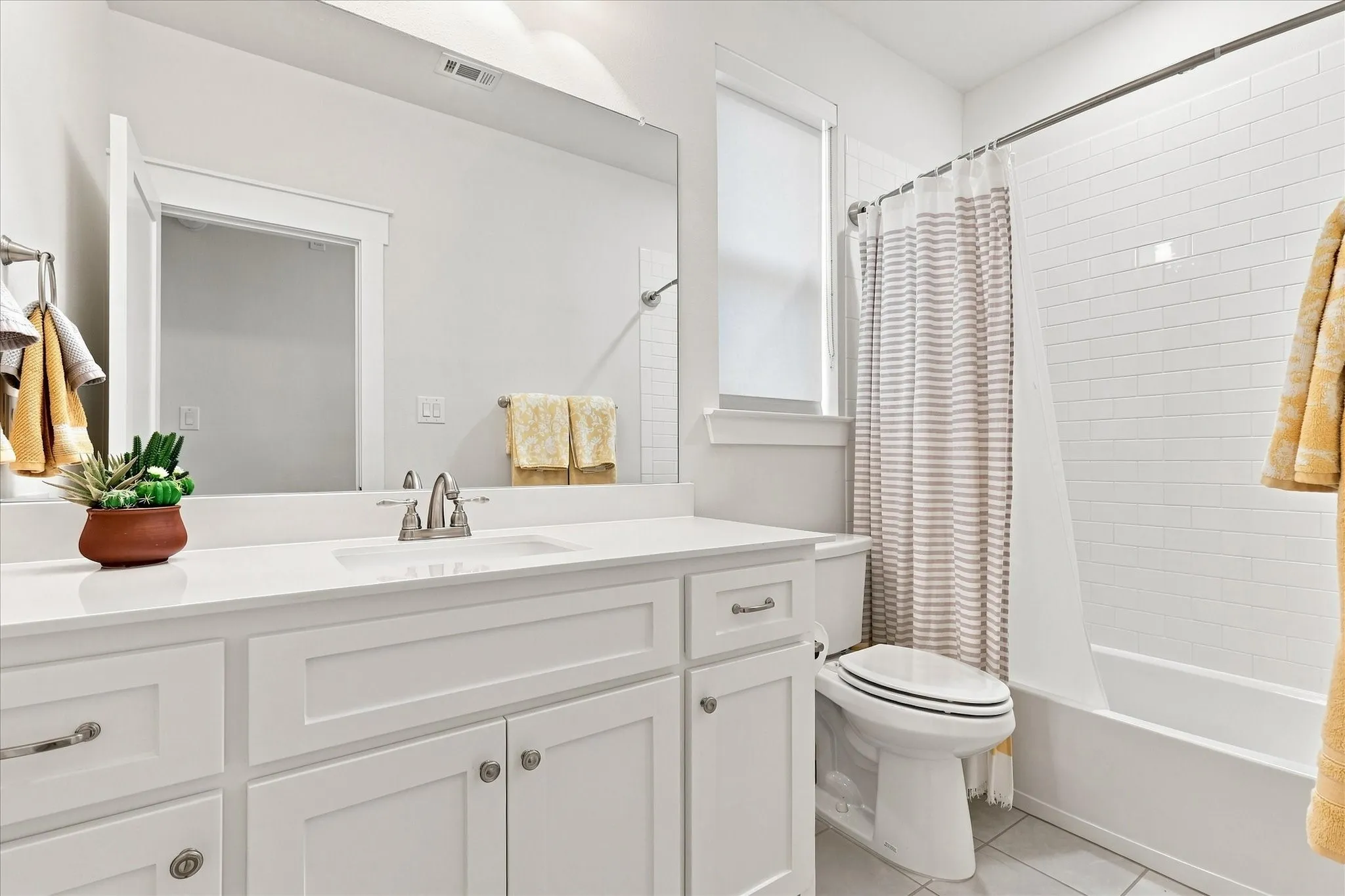 Bathroom featuring a white vanity with an integrated sink, polished chrome faucet, and a large wall-mounted mirror