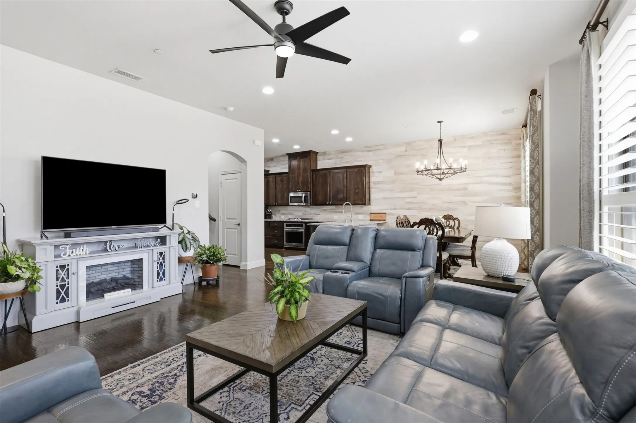 Spacious living area featuring dark wood-finish flooring, a contemporary ceiling fan, and recessed lighting