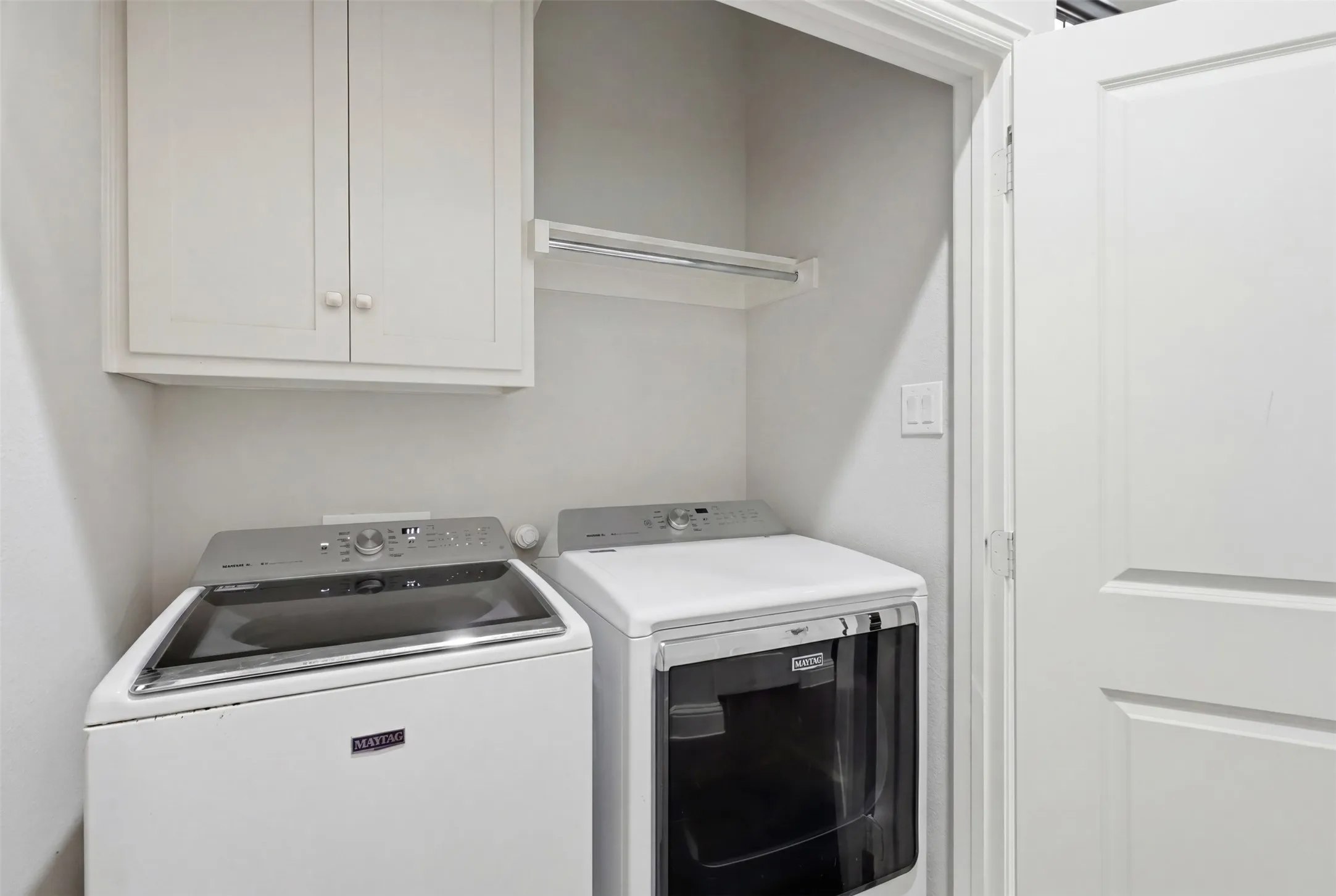 Built-in upper cabinetry, white interior walls, and a hanging rod