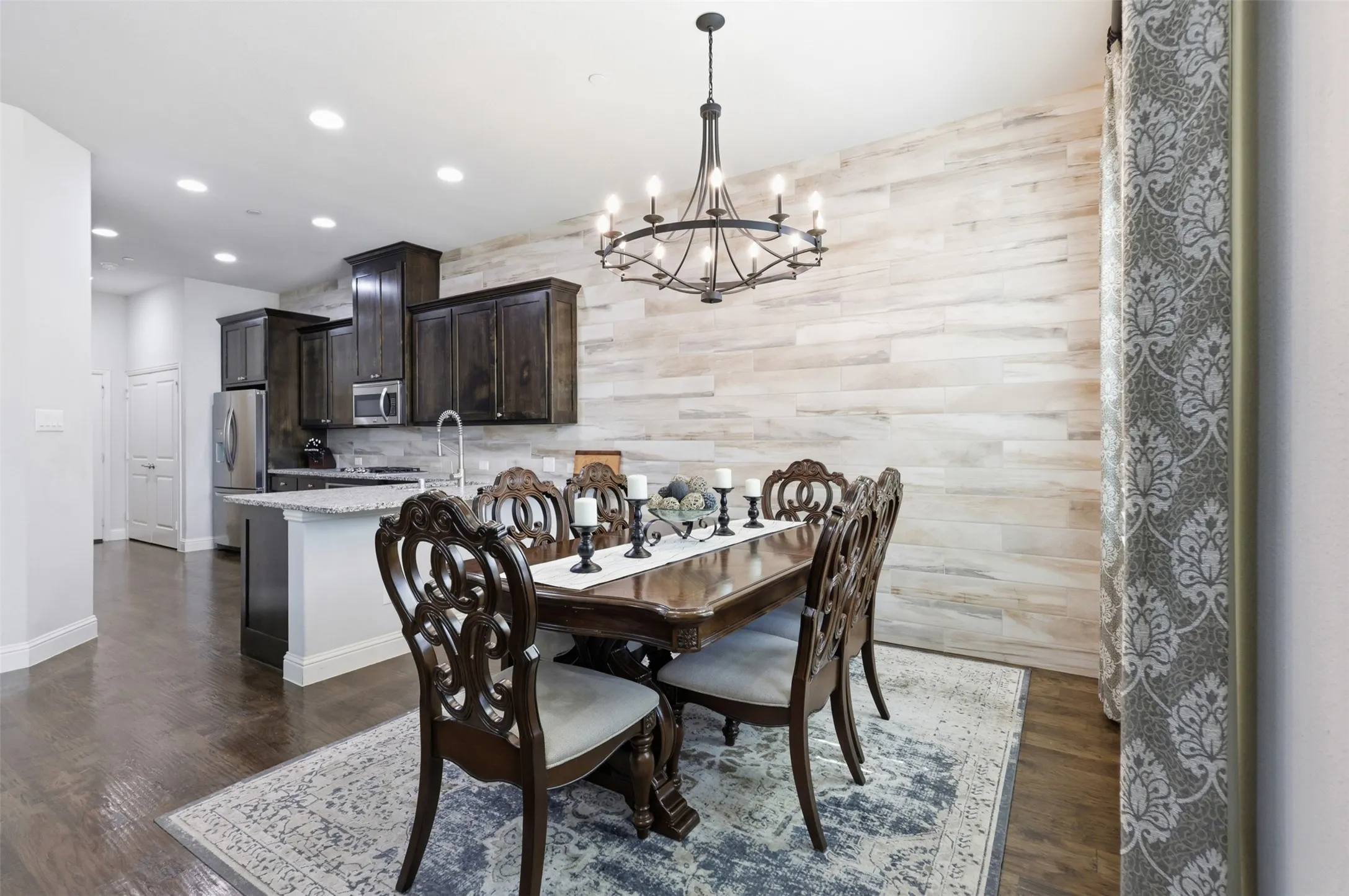 Open-concept room featuring wood-finish flooring, recessed lighting, and a textured accent wall