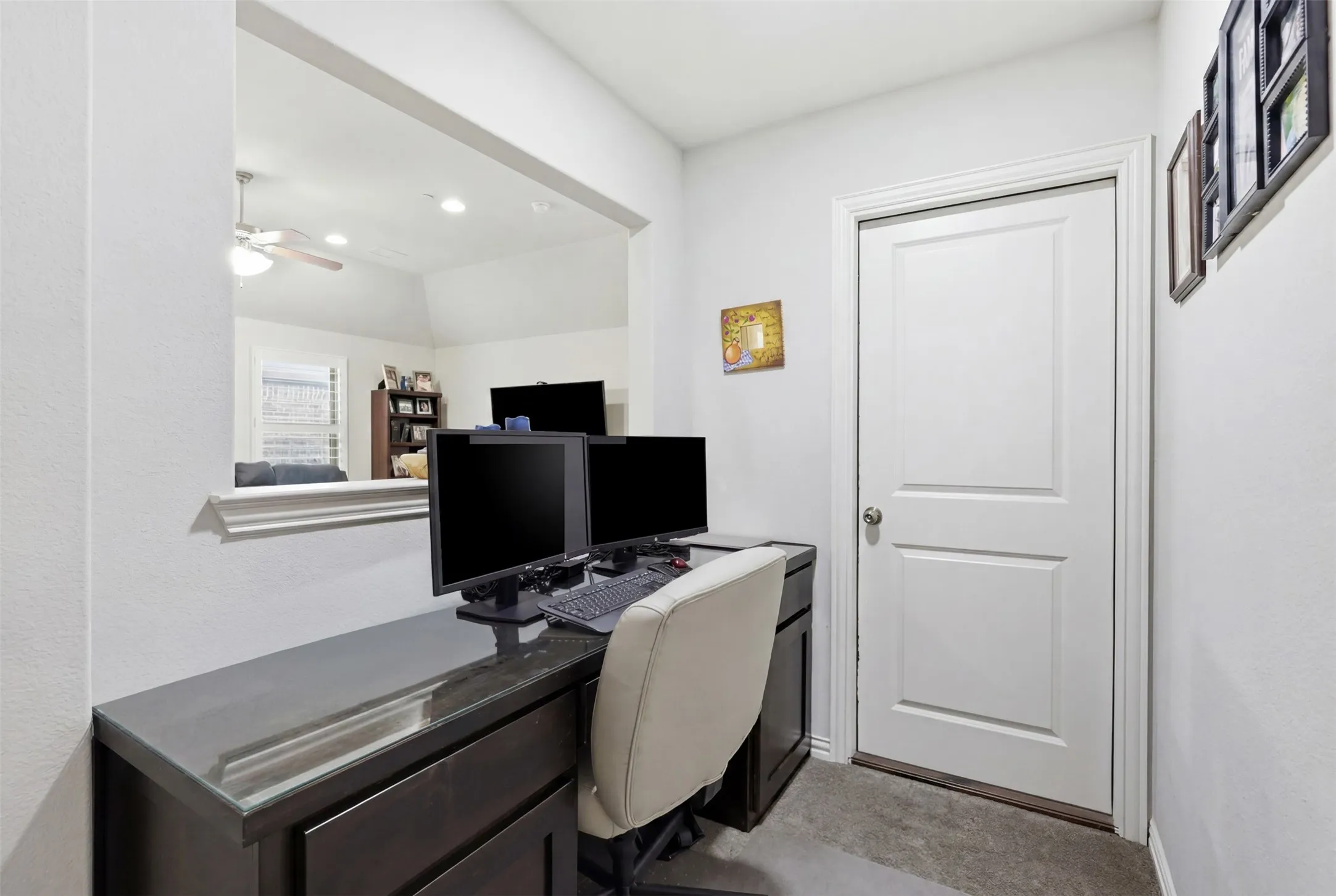 Built-in dark wood-finish desk with a glossy countertop, white paneled door, and recessed lighting