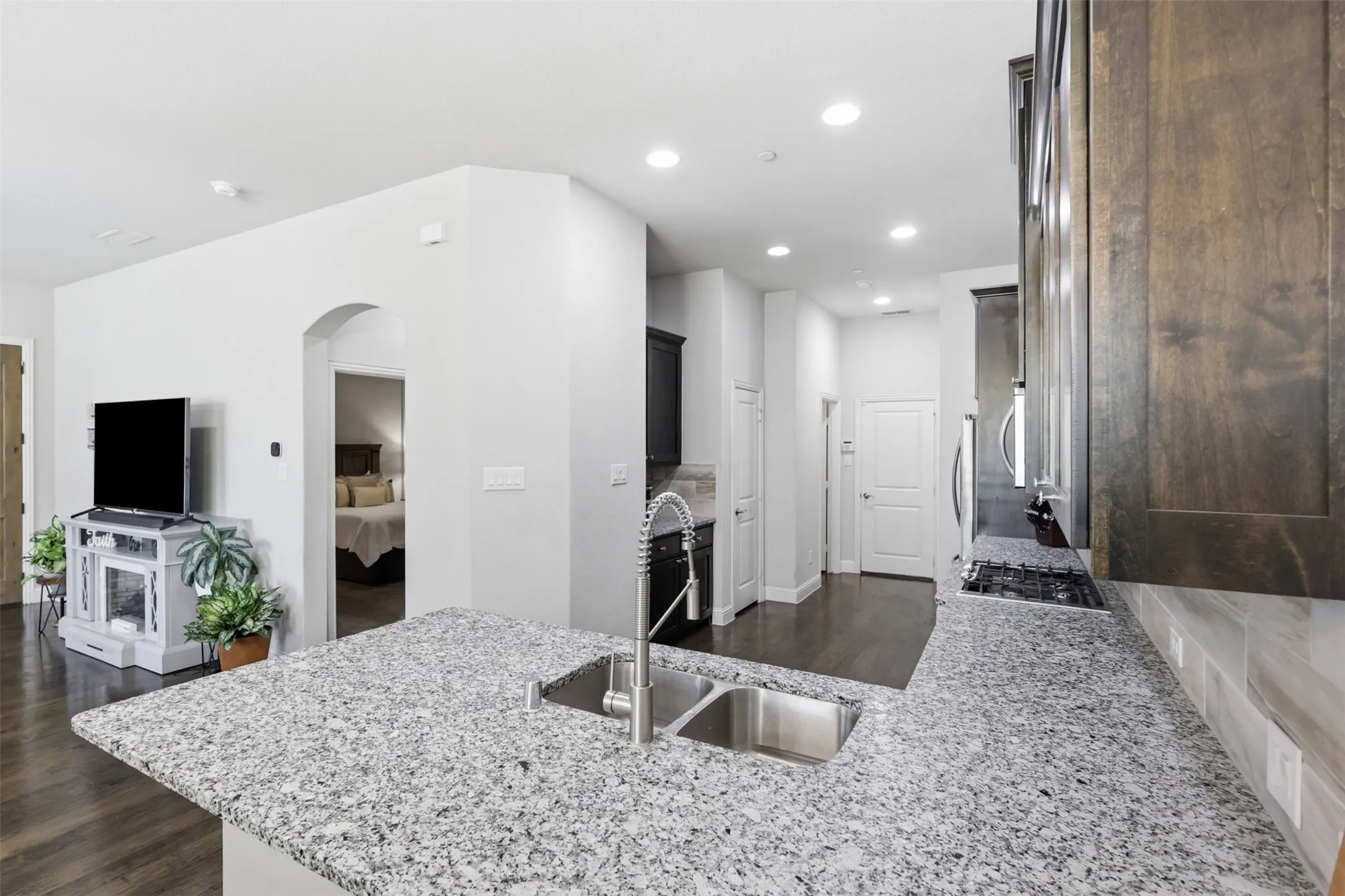 Kitchen featuring a dual basin stainless steel sink, pull-down faucet, granite-style countertops, wood-finish cabinetry, and stainless steel appliances