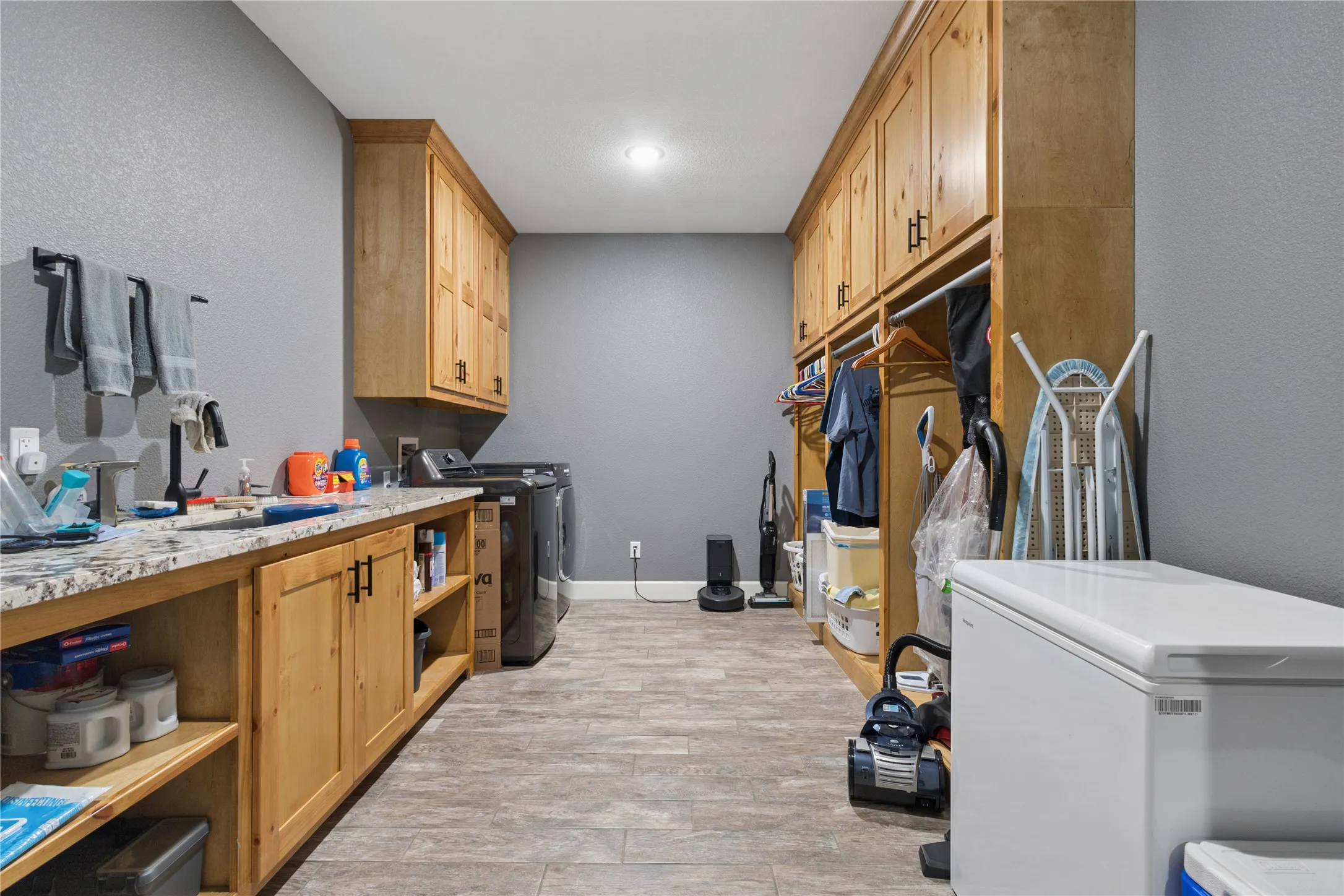 Laundry space with wood-finish cabinetry, a built-in counter with a light-toned countertop, and wood-finish flooring