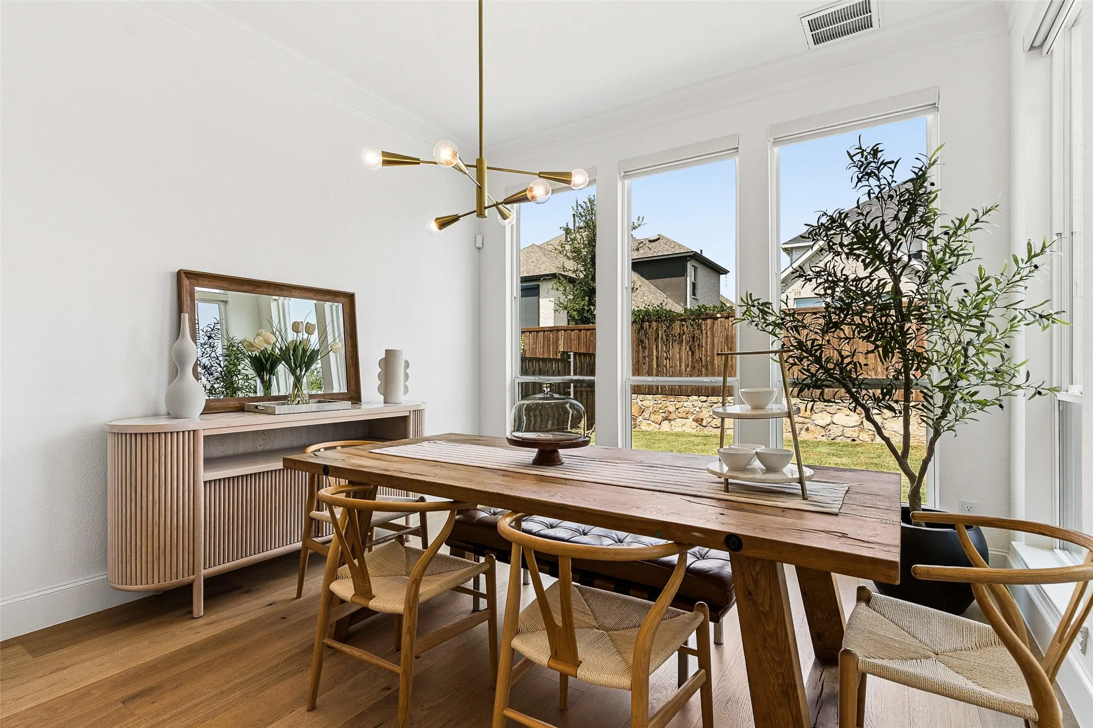 Spacious dining area featuring wood-finish flooring, a modern linear chandelier, and expansive windows