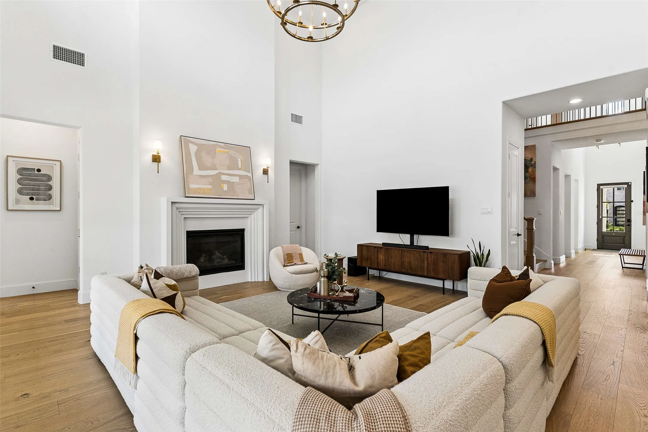 Vaulted ceilings, wood-finish flooring, a fireplace with a white mantel, an overhead decorative light fixture, and recessed lighting