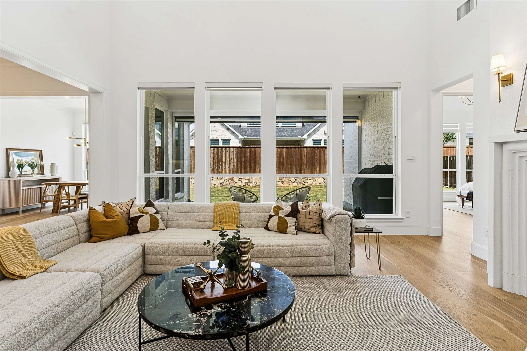 High ceilings, expansive windows, wood-finish flooring, a contemporary fireplace, and a private backyard with a manicured lawn