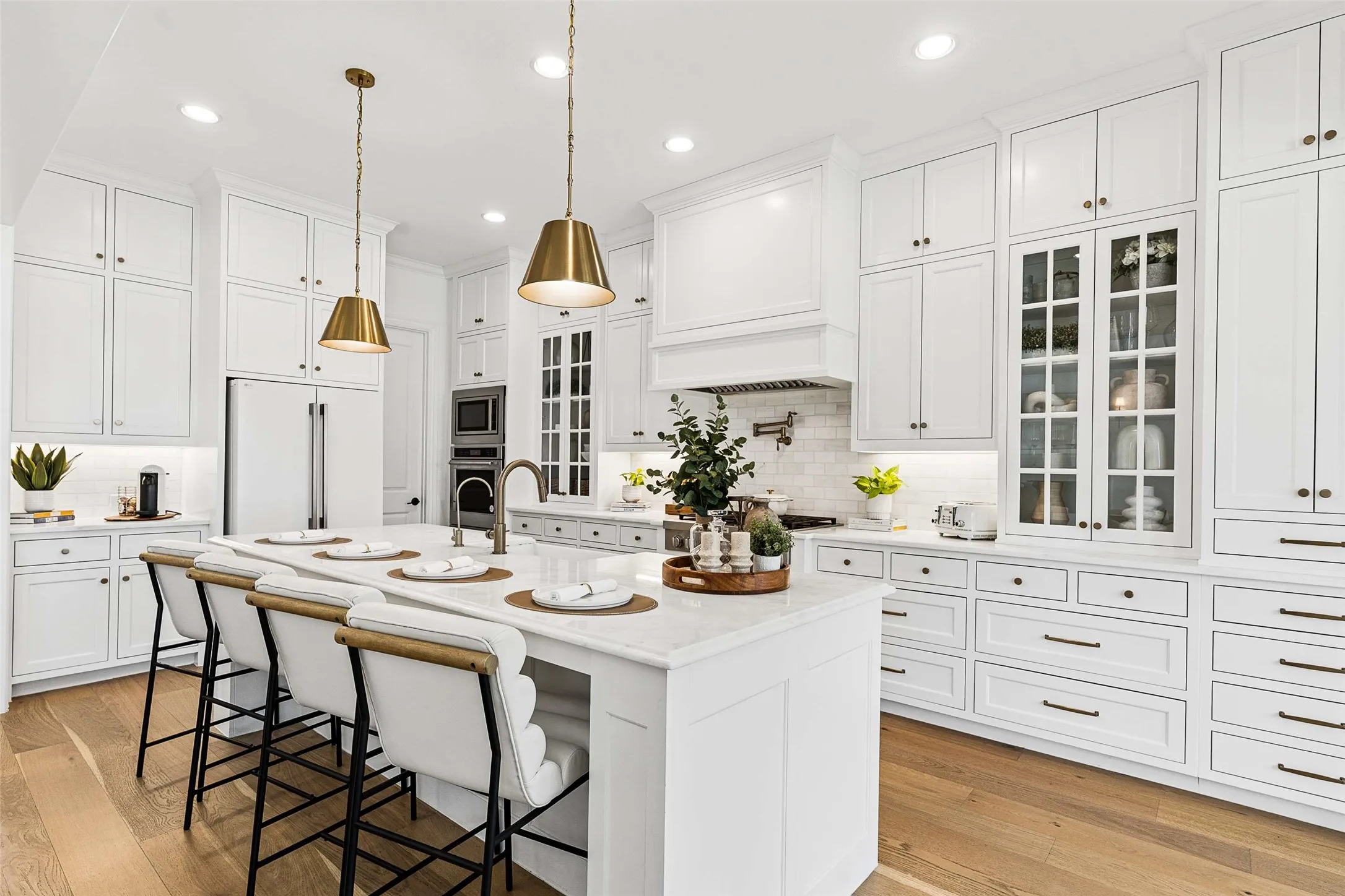 Gourmet kitchen with white cabinetry, a large center island, integrated appliances, and wood-finish flooring