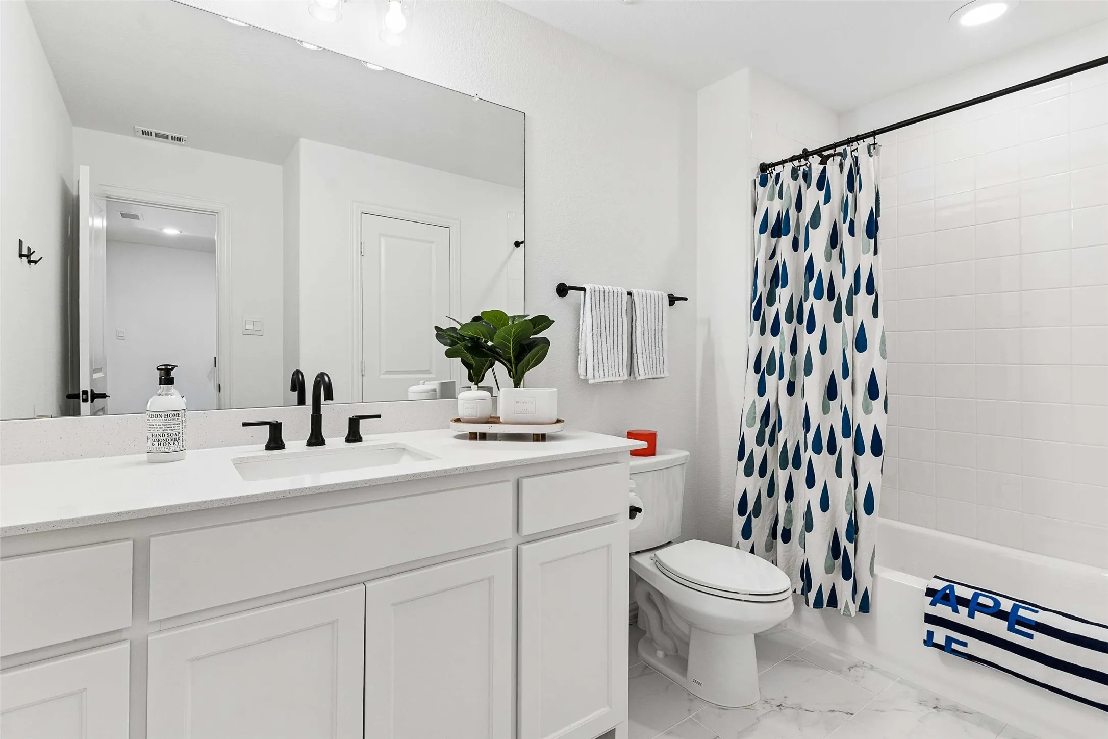 White vanity with matte black faucet, integrated sink, and expansive wall mirror