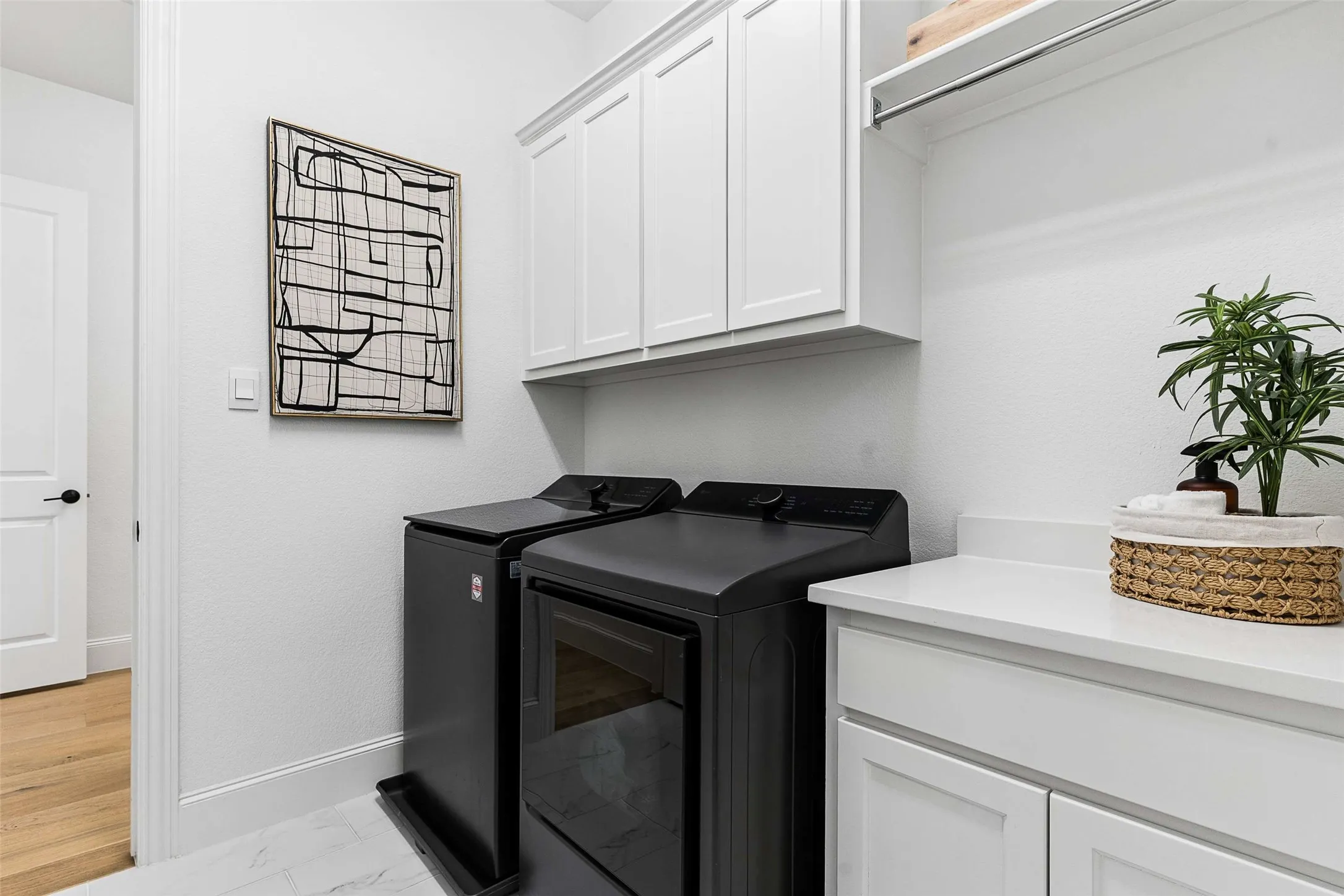 Laundry area featuring white cabinetry, a white countertop, and open shelving with a hanging rod