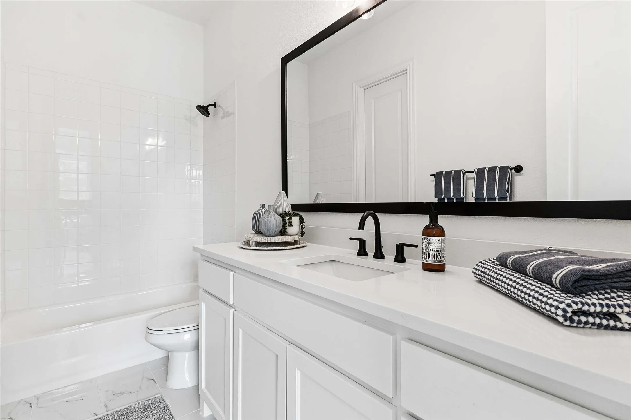 White vanity with integrated sink, matte black faucet, and a large framed mirror