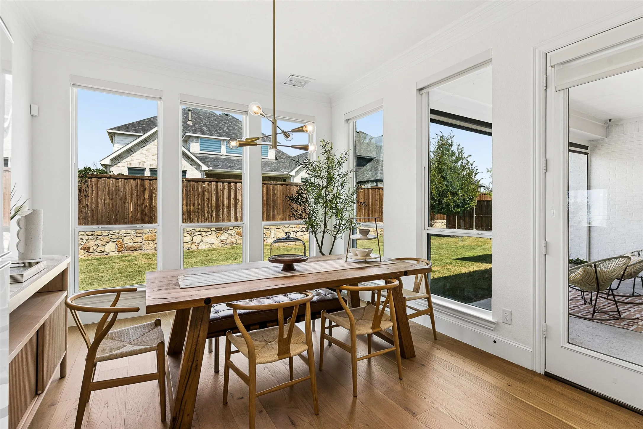 Expansive window wall, wood-finish flooring, contemporary chandelier, glass-paneled door, built-in shelving with stone countertop