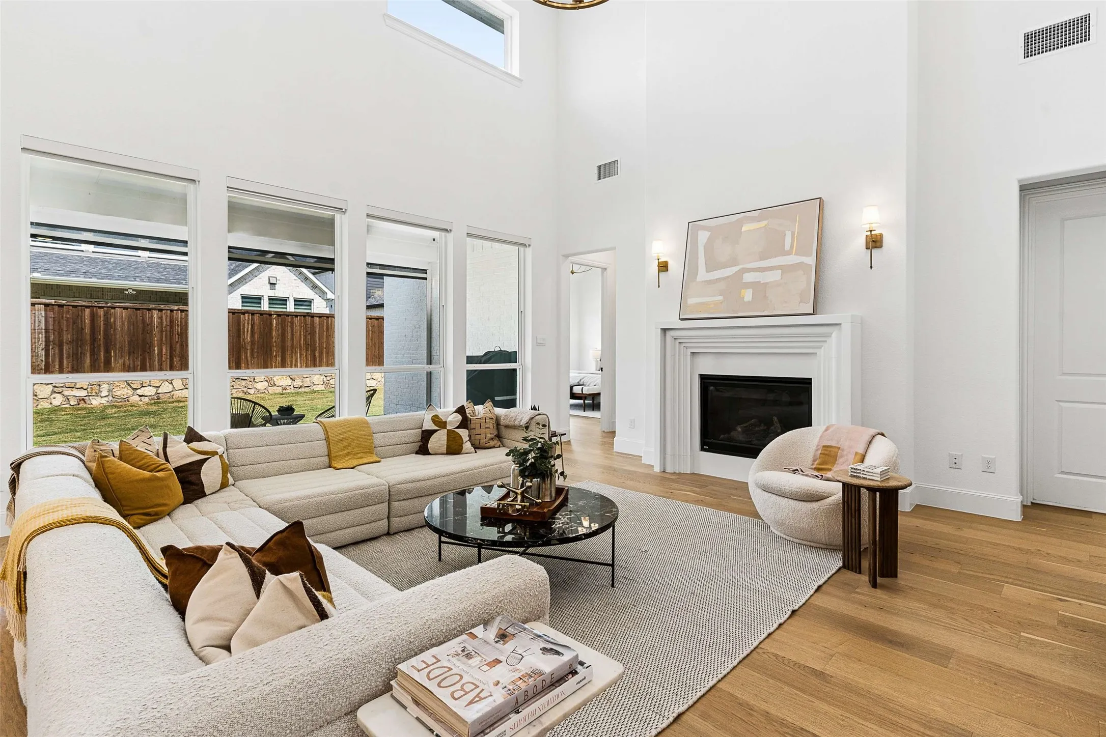 Soaring ceilings, expansive window wall, wood-finish flooring, built-in fireplace, and integrated wall sconces