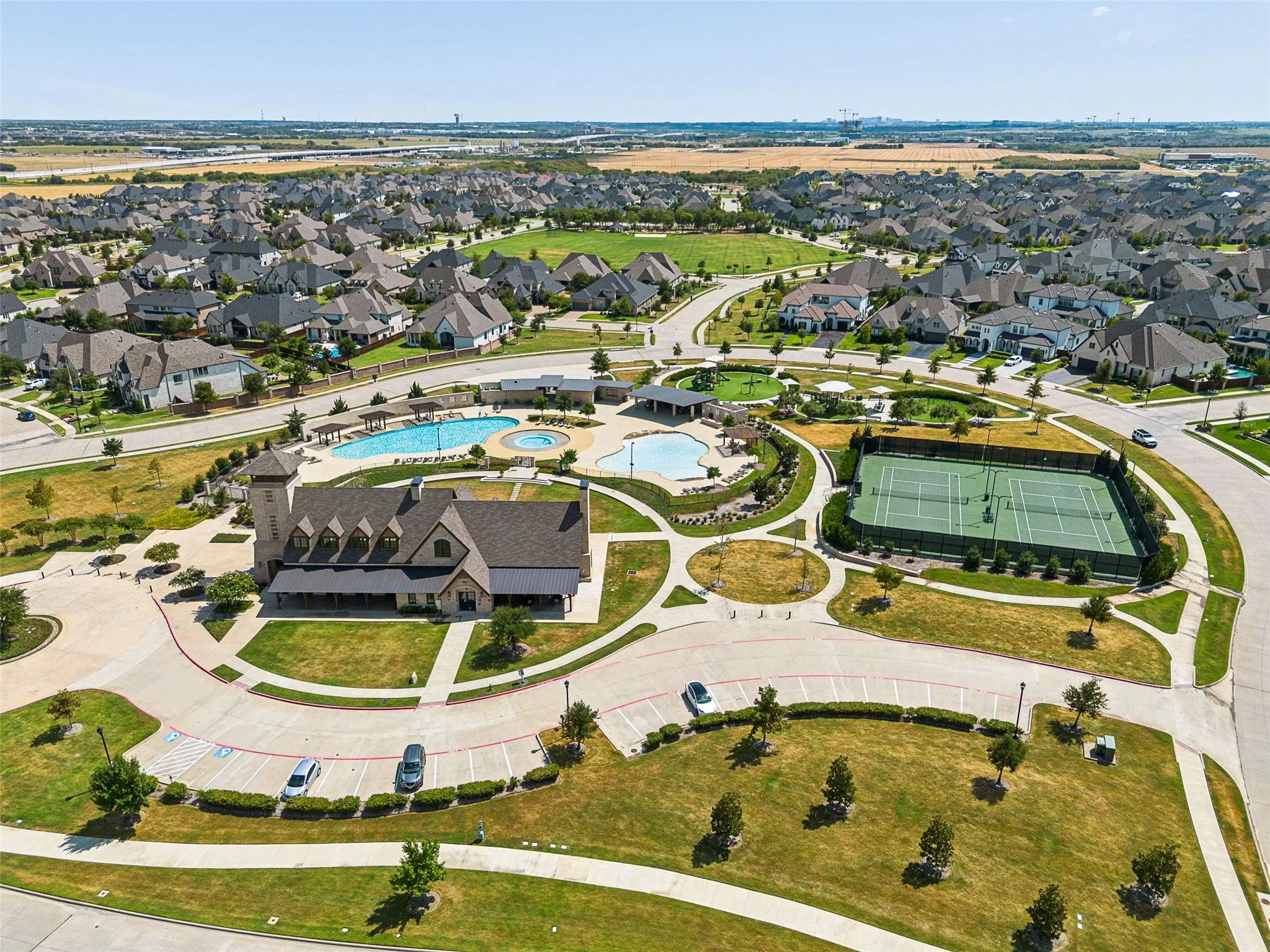Community clubhouse with swimming pools, tennis courts, and surrounding residential properties