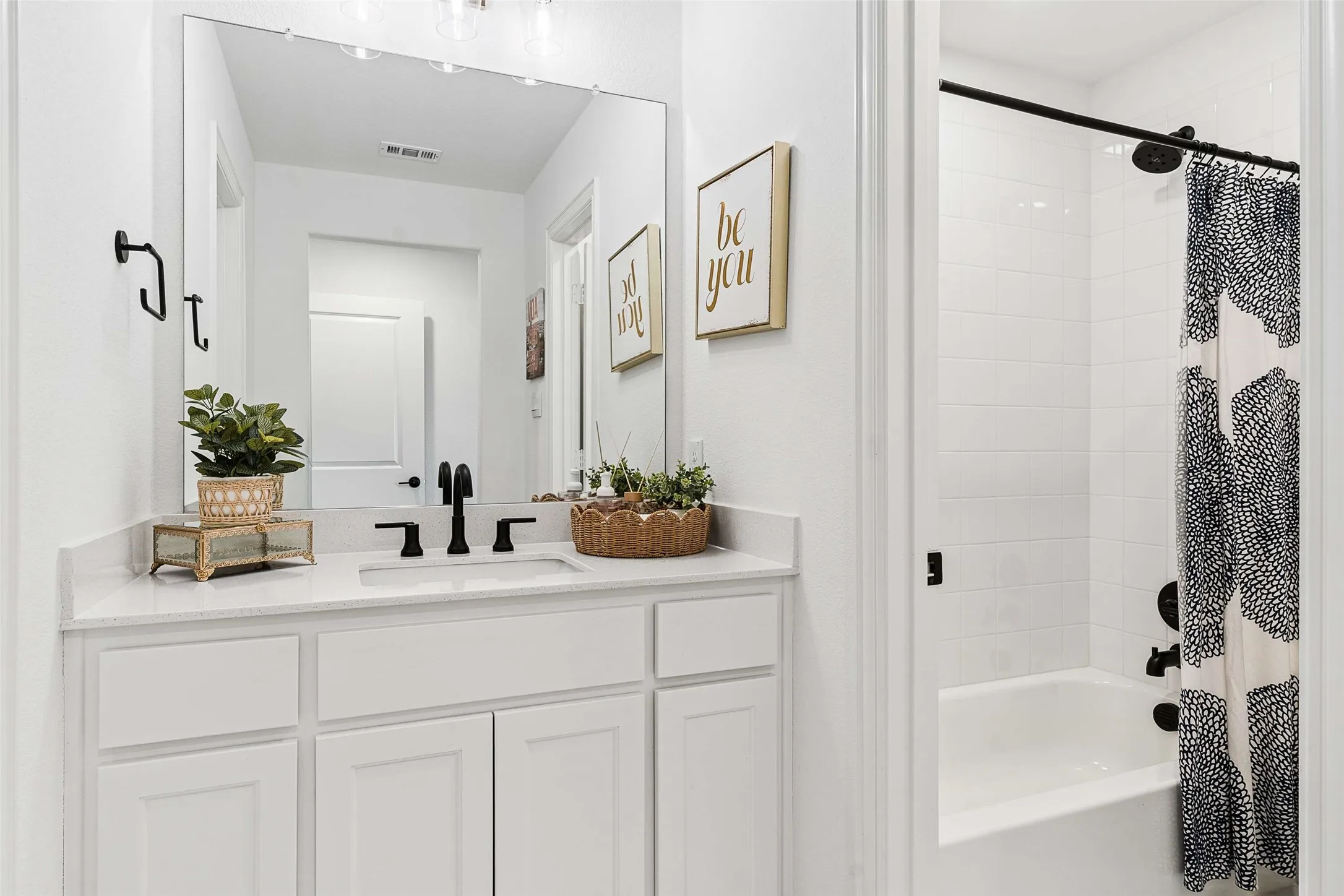 White vanity with shaker-style cabinetry, a built-in sink, and a light-toned countertop