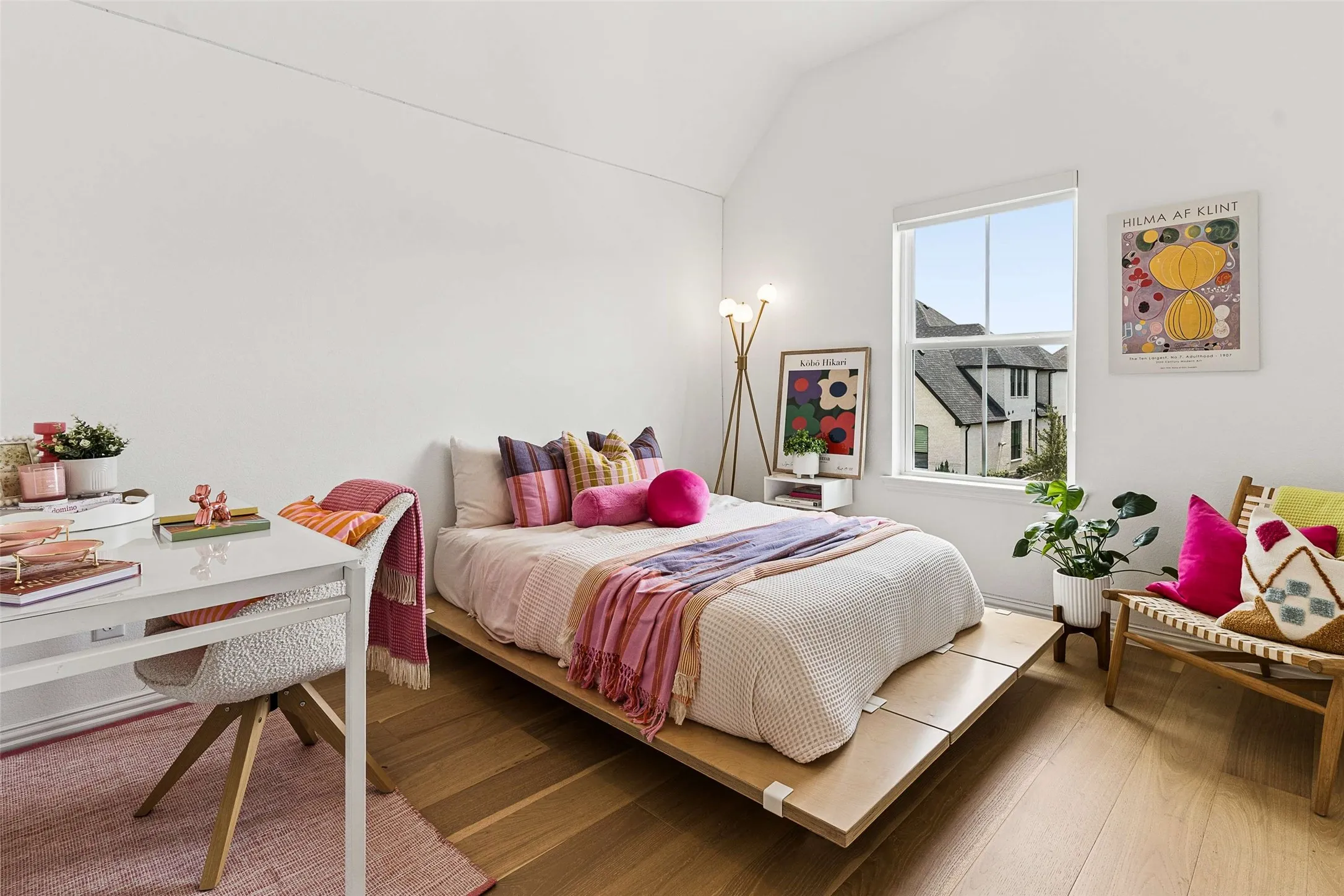 Bright room with a large window, vaulted ceiling, and wood-finish flooring