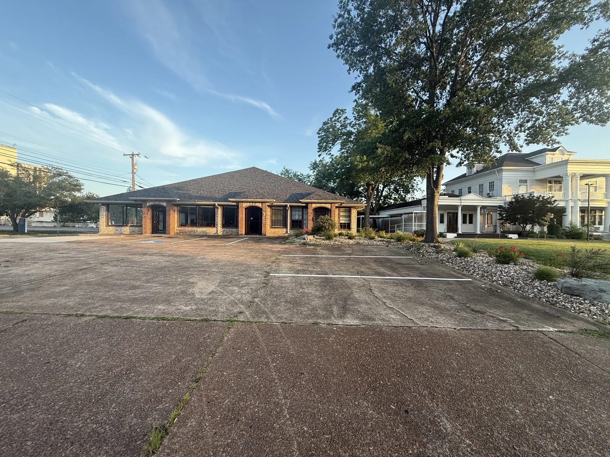 Commercial property with a brick and stone facade, multiple large windows, and a dark shingle roof