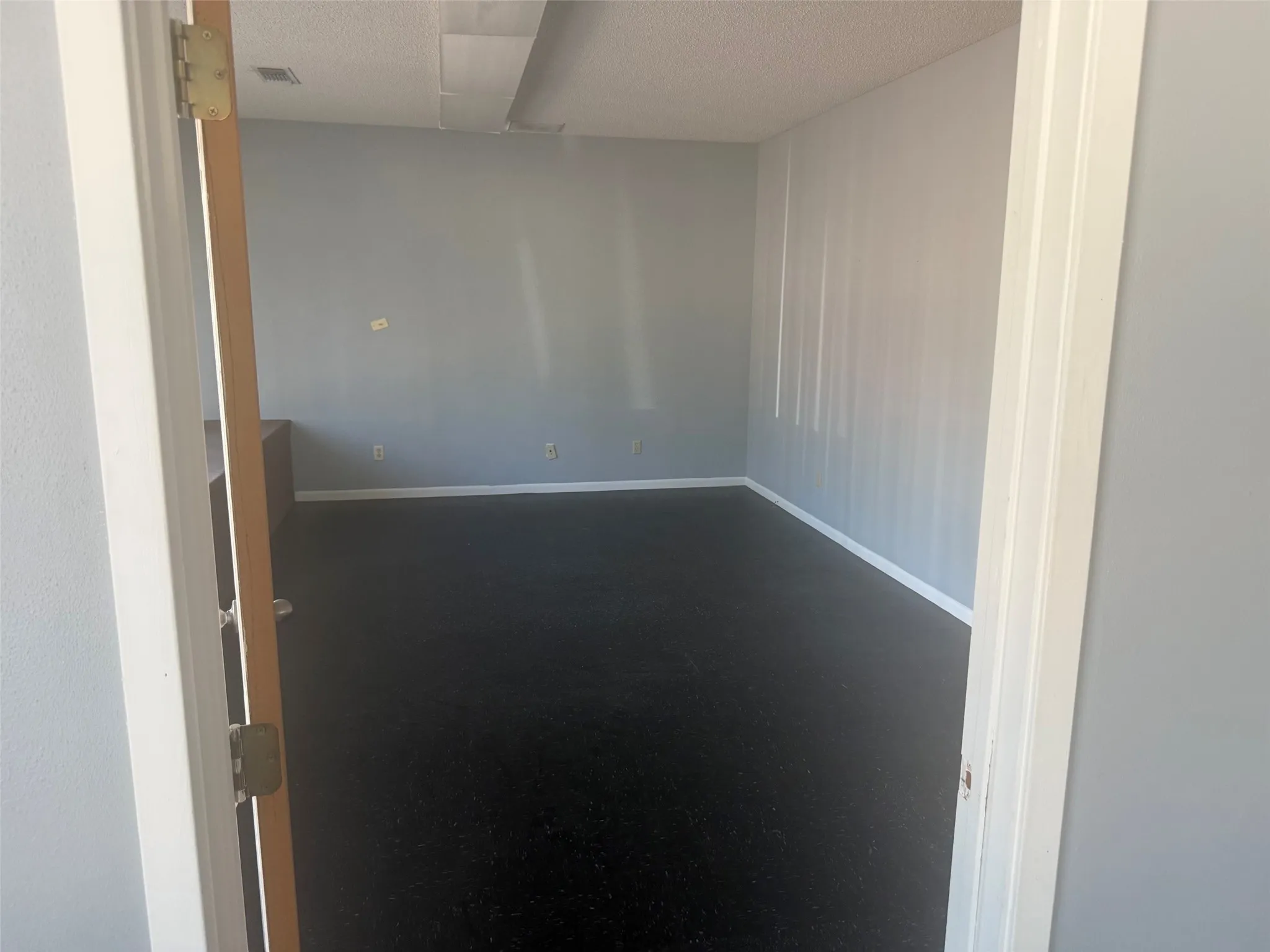 Room featuring light gray walls, dark flooring, and white baseboards