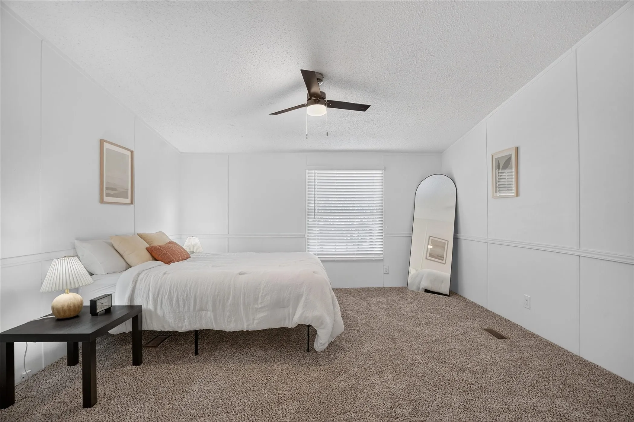 Carpeted bedroom featuring white paneled walls and a ceiling fan with integrated lighting