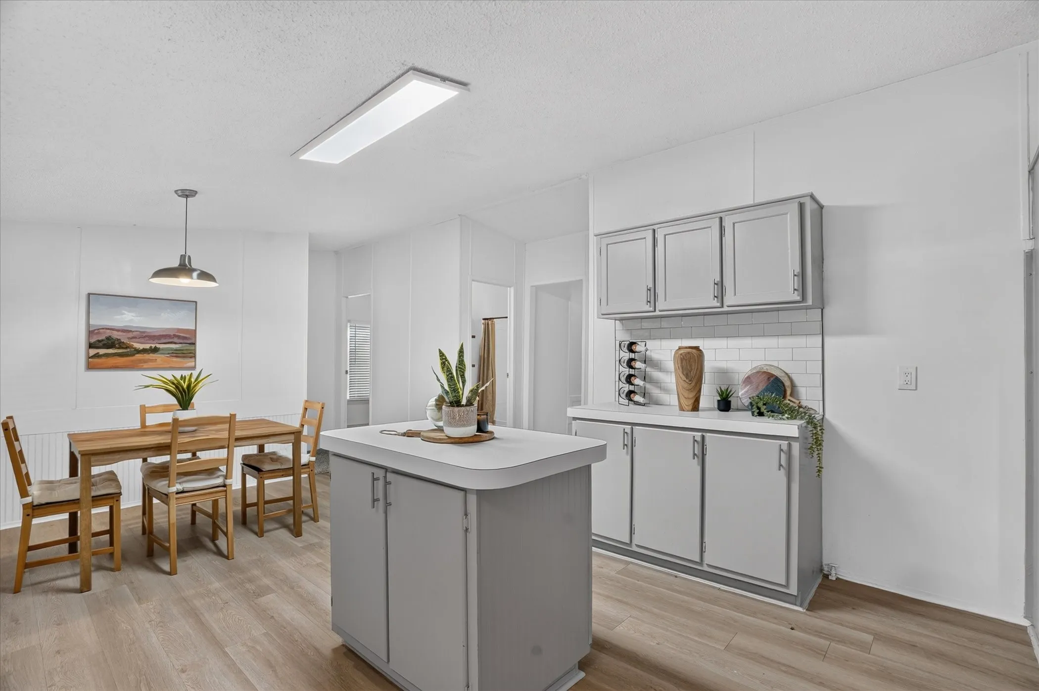 Kitchen island with countertop, wood-finish flooring, subway tile backsplash, and built-in cabinetry