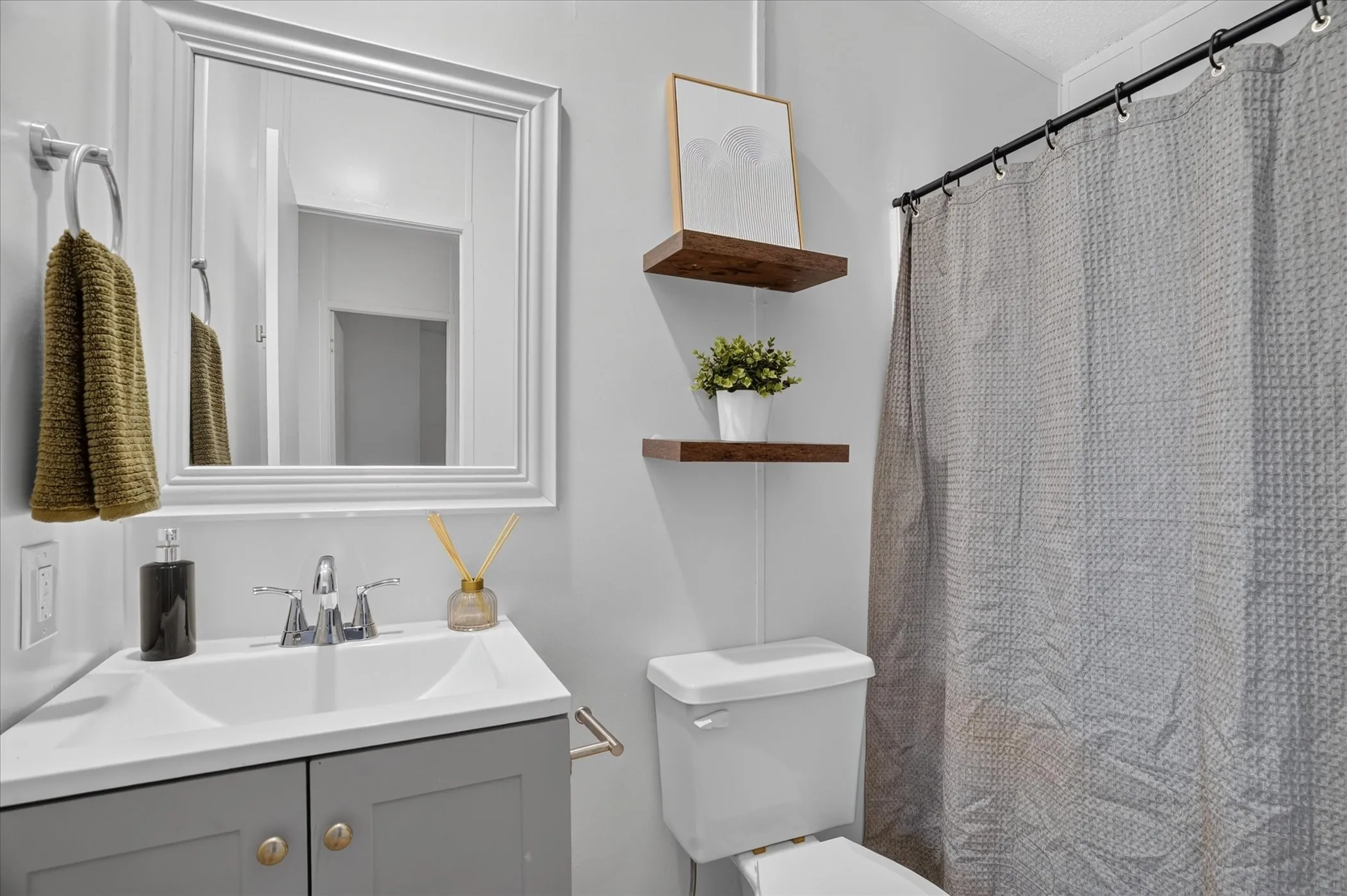Renovated bathroom featuring a gray vanity with brass hardware, white ceramic vessel sink, and chrome faucet