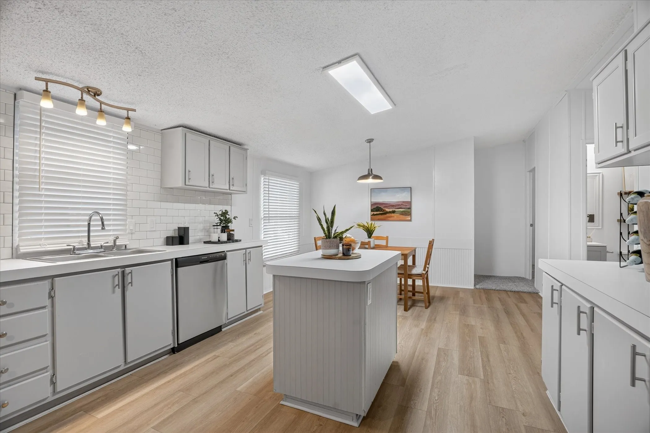 Bright, contemporary kitchen featuring white cabinetry, stainless steel appliances, and a large island with wood-finish countertop