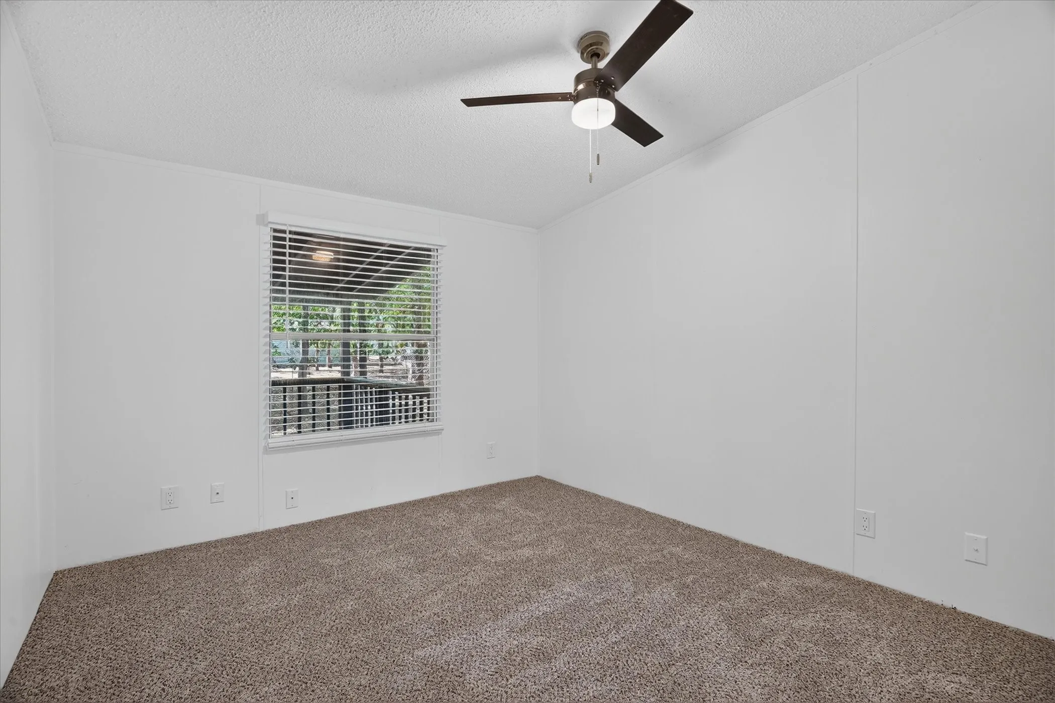 White walls with a textured ceiling, brown carpet flooring, and a ceiling fan with integrated lighting