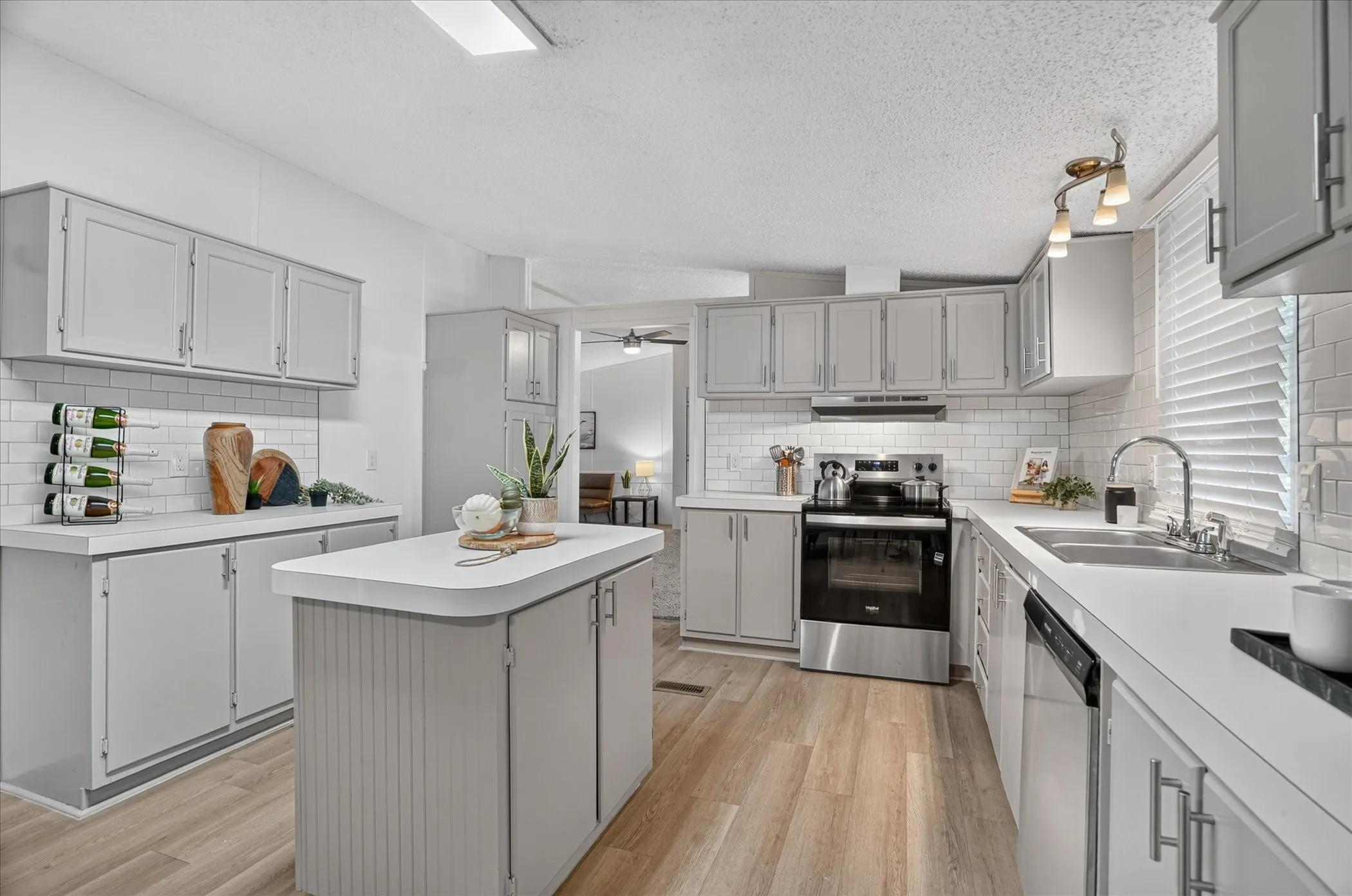 Kitchen featuring a central island, light gray cabinetry, white countertops, stainless steel appliances, and a subway tile backsplash