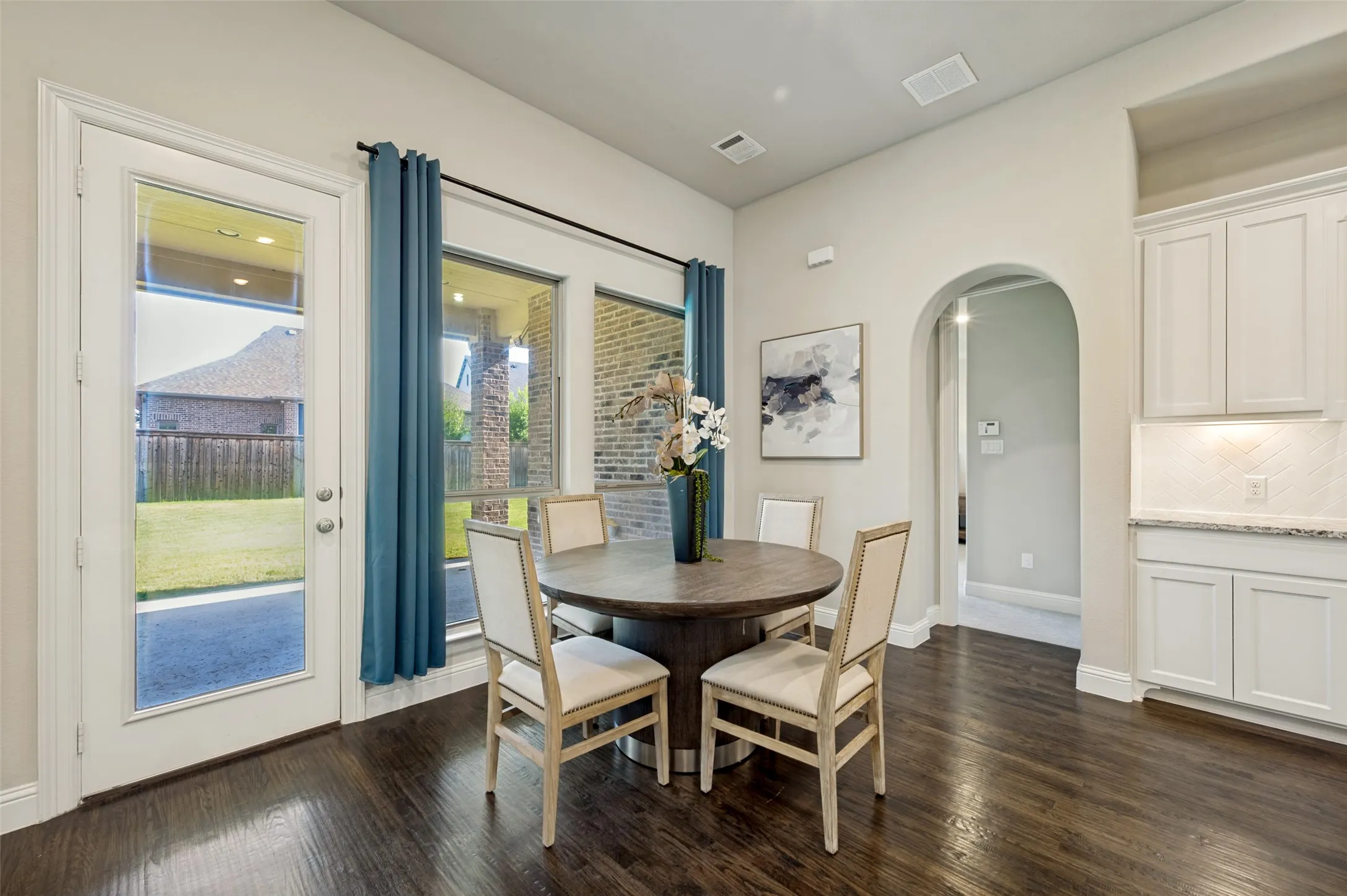 The light-filled breakfast area offers a warm and inviting setting for casual dining, framed by expansive windows, rich hardwood floors, and serene views of the covered patio and backyard. Seamlessly connected to the kitchen, this airy space is ideal for everyday living while blending comfort, function, and effortless style.