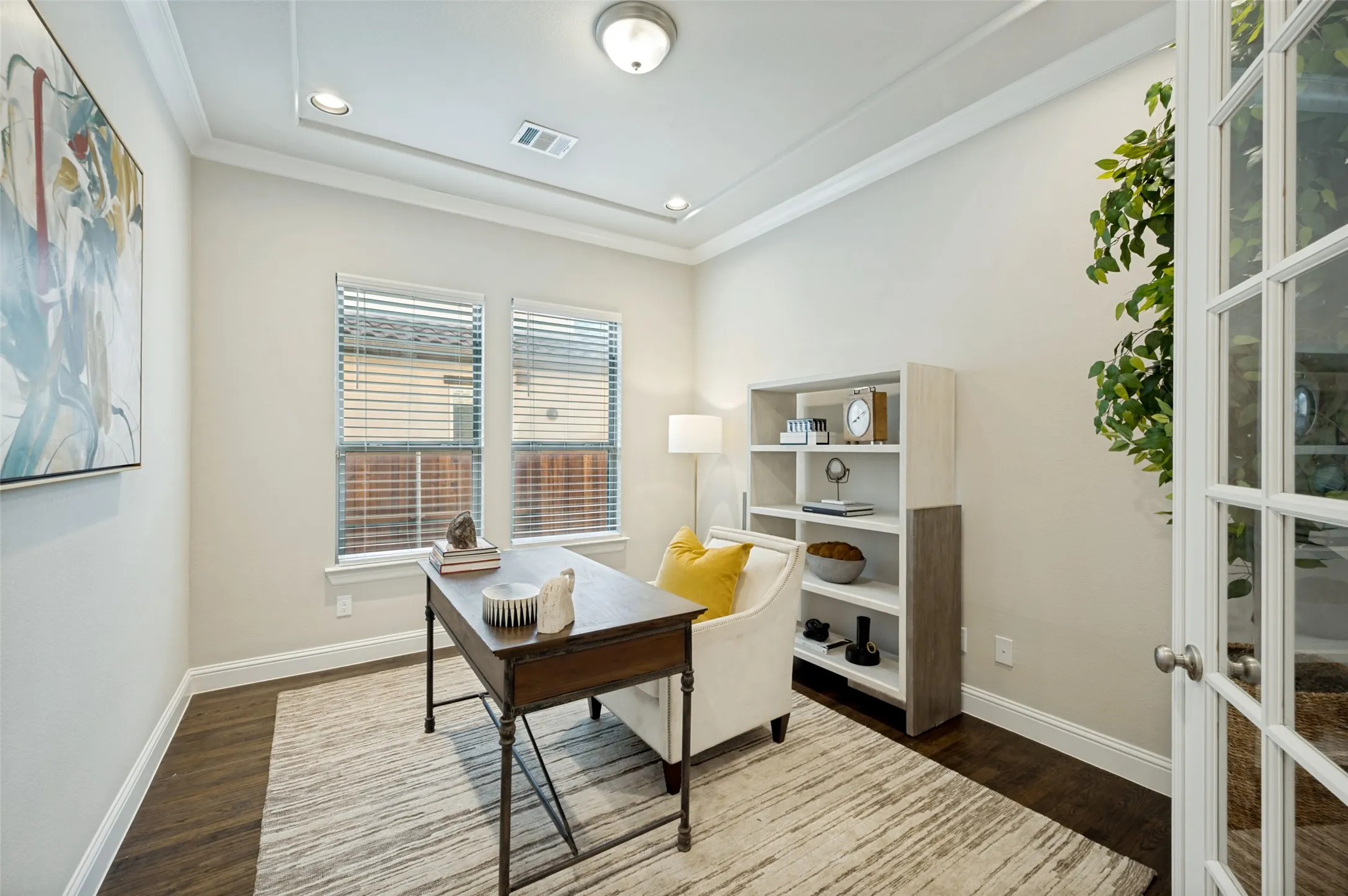 A private home office with French doors and a tray ceiling offers the perfect blend of sophistication and function. Rich hardwood floors, abundant natural light, and a quiet front-of-home setting create an ideal space for working from home, managing daily tasks, or enjoying a stylish reading retreat.