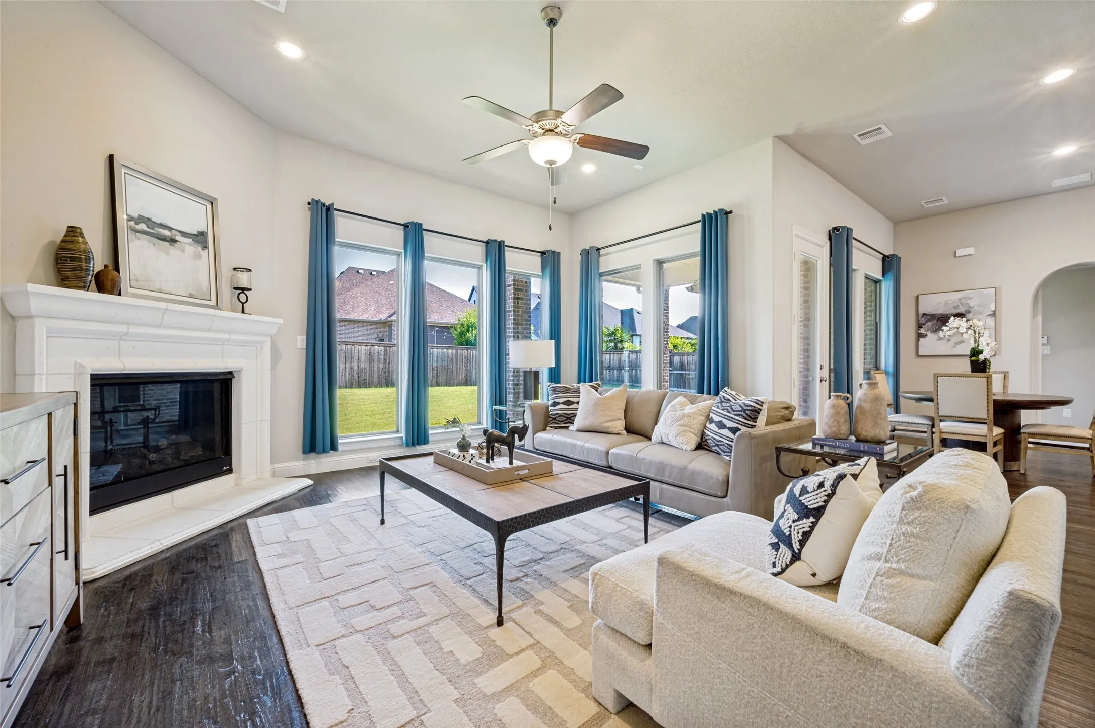Bathed in natural light from walls of windows, the spacious family room offers an inviting blend of comfort and elegance. A striking corner fireplace anchors the space, while the open-concept design flows seamlessly into the kitchen and breakfast area, creating the perfect setting for both relaxed everyday living and effortless entertaining.