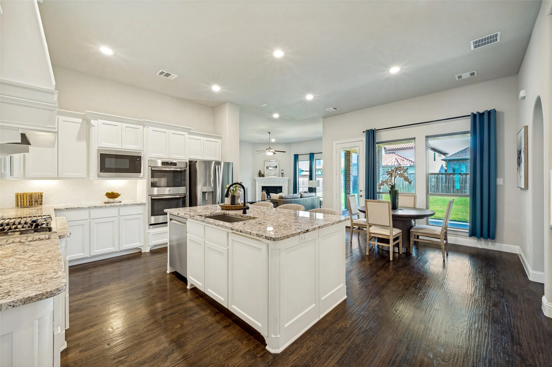 The heart of the home unfolds in this beautifully designed open-concept living space, where the chef’s kitchen, breakfast area, and family room come together with effortless flow. Anchored by an oversized island and surrounded by rich hardwood floors, expansive windows, and views of the covered patio and backyard, this light-filled space was designed for both elevated entertaining and comfortable everyday living.