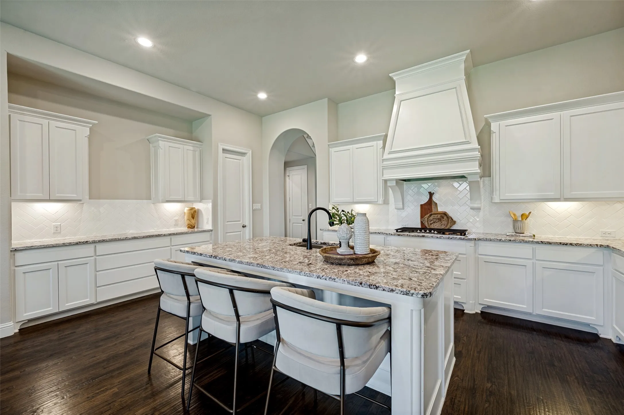 A true centerpiece of the home, the chef’s kitchen impresses with an oversized granite island, abundant custom cabinetry, and a striking statement vent hood that draws the eye upward. Thoughtfully designed for both everyday living and elevated entertaining, the space offers extensive prep and serving areas, designer finishes, and seamless flow into the surrounding living spaces—creating a warm, sophisticated heart of the home.