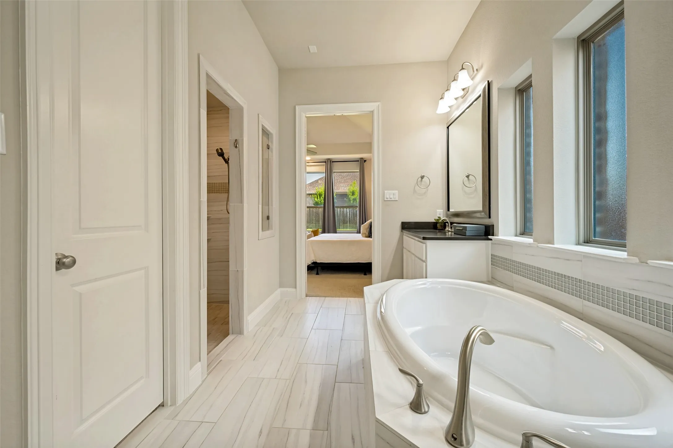 The spa-inspired primary bath offers a serene retreat with a soaking tub, oversized walk-in shower, dual vanities, and timeless finishes throughout. Soft natural light, clean architectural lines, and a bright, airy design create a luxurious space designed for both relaxation and everyday comfort.