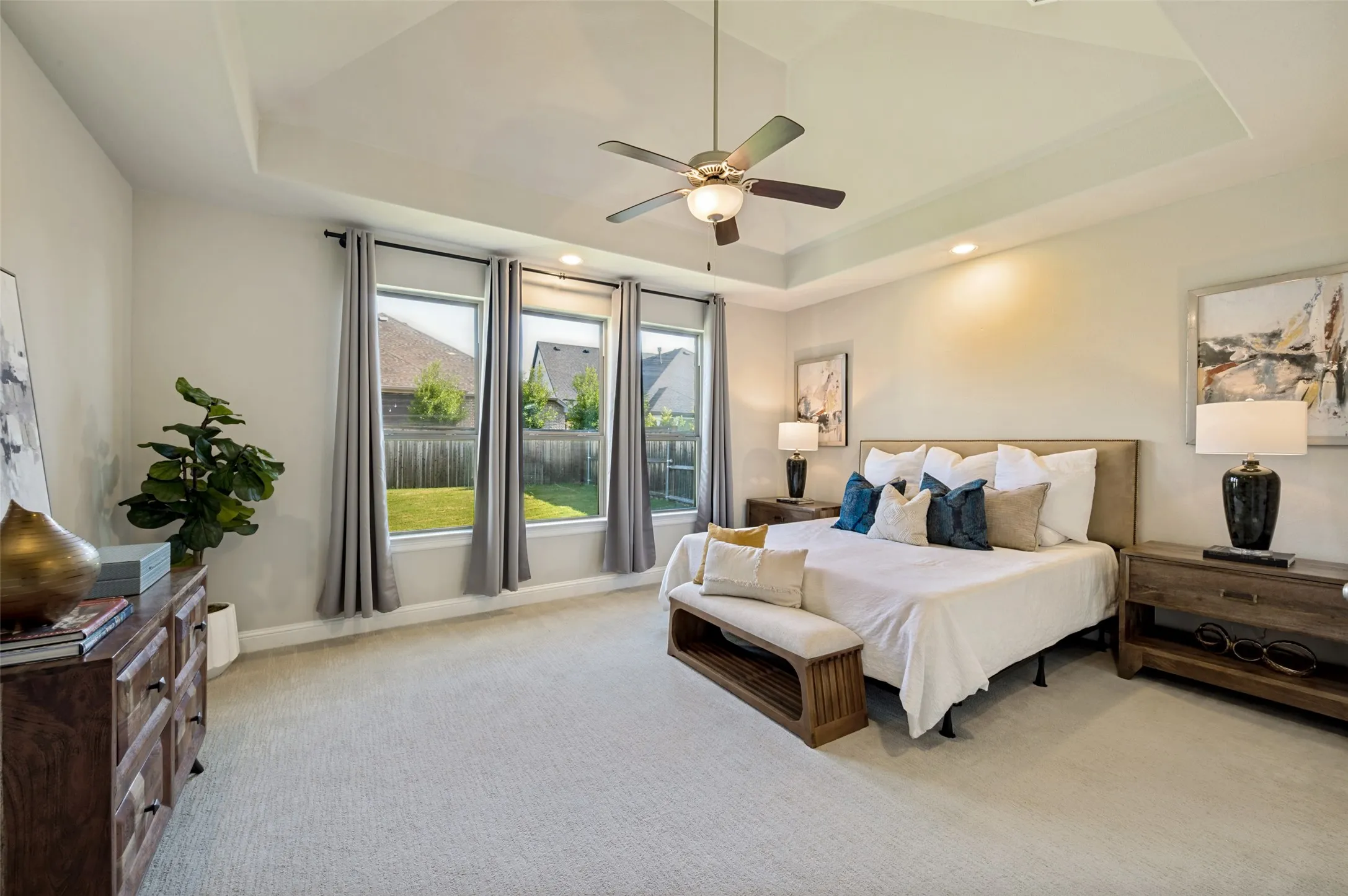 The spacious primary suite offers a serene retreat with room to unwind, featuring a tray ceiling, soft natural light, and generous proportions that create an airy, luxurious feel. Overlooking the backyard, this private haven blends comfort and sophistication with ample space for a sitting area and a true sense of everyday escape.