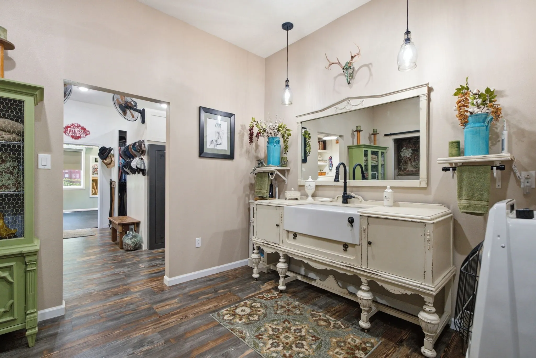 Wood-finish flooring, drop-in sink, vanity with storage, two pendant light fixtures, and a large wall mirror
