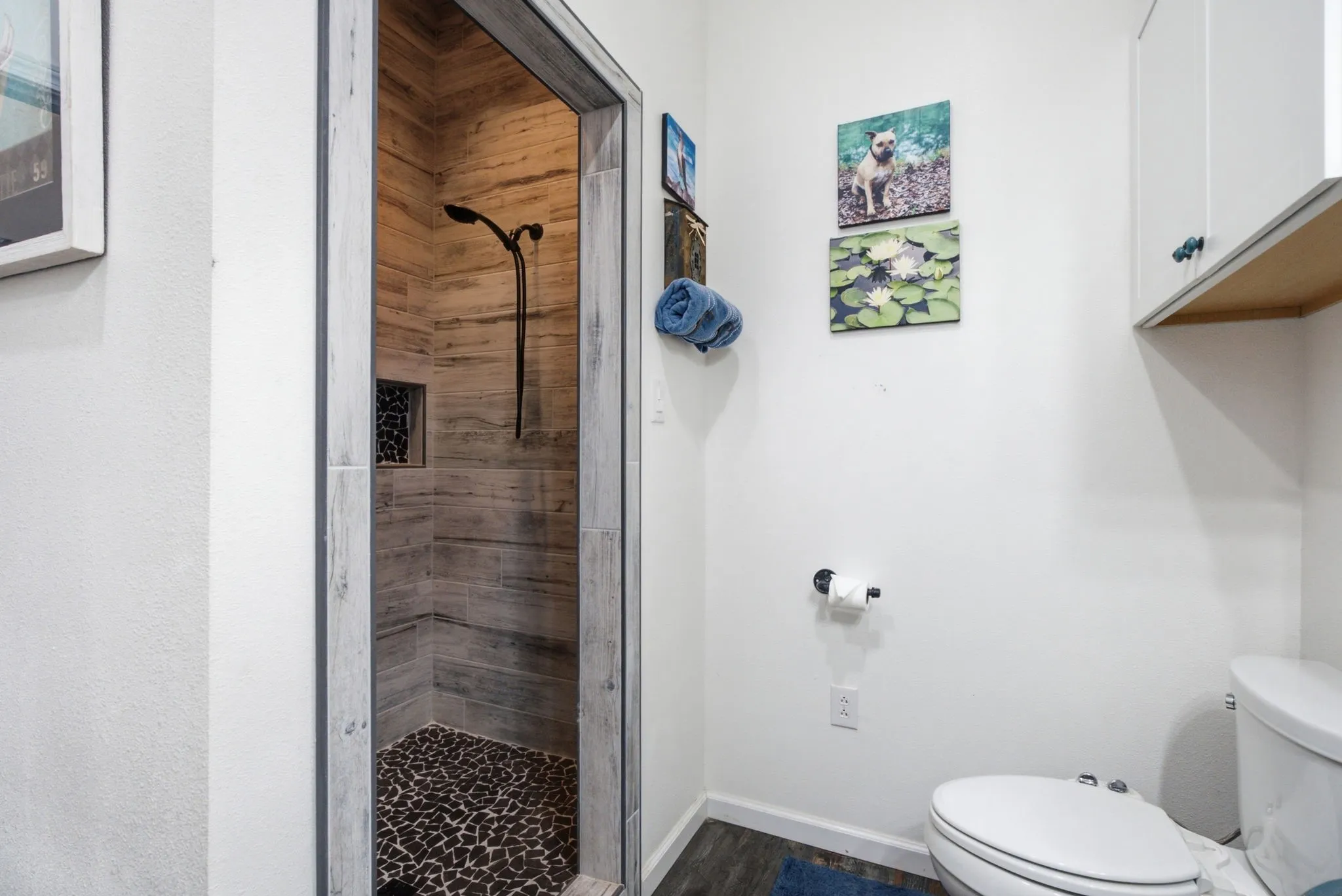 Walk-in shower with wood-look tile surround and a pebble tile floor