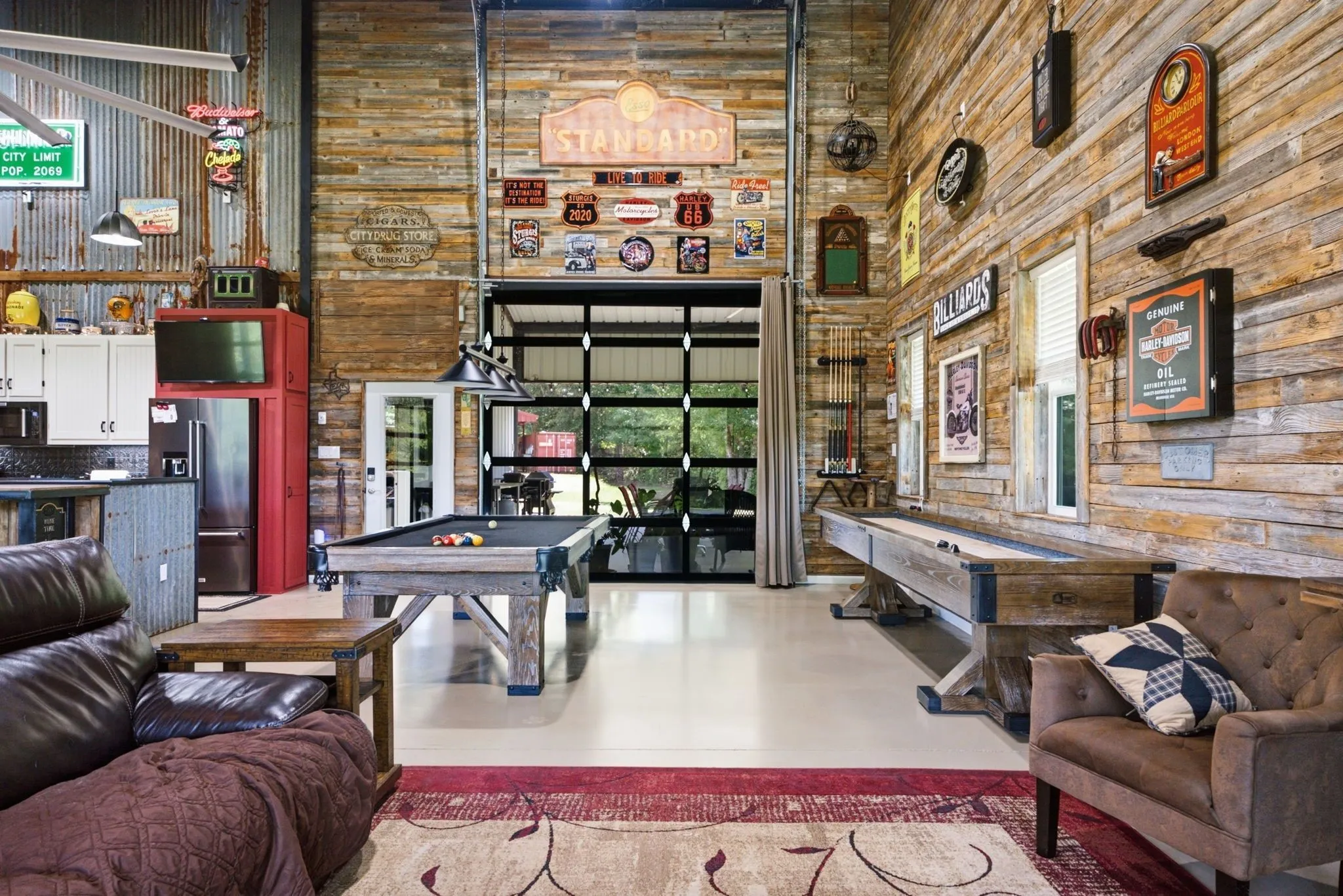 High ceilings, corrugated metal wall paneling, wood-finish wall paneling, overhead garage door with glass panes, and a built-in kitchen area