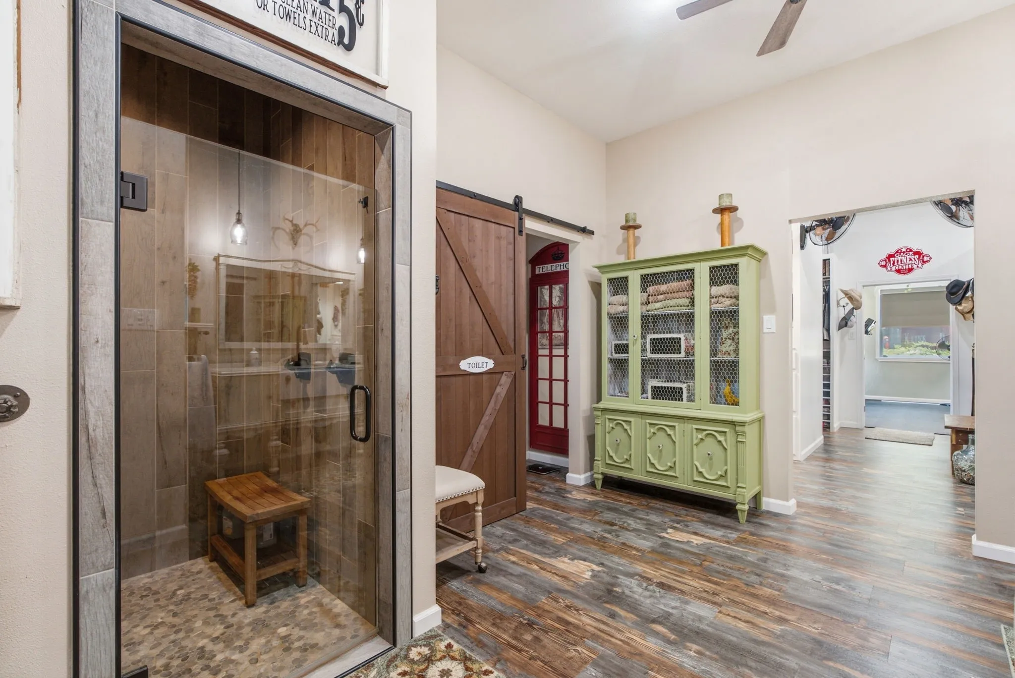 Primary bathroom suite showcasing a custom walk-in shower with wood-finish barn door, stone tile surround, and integrated bench seating