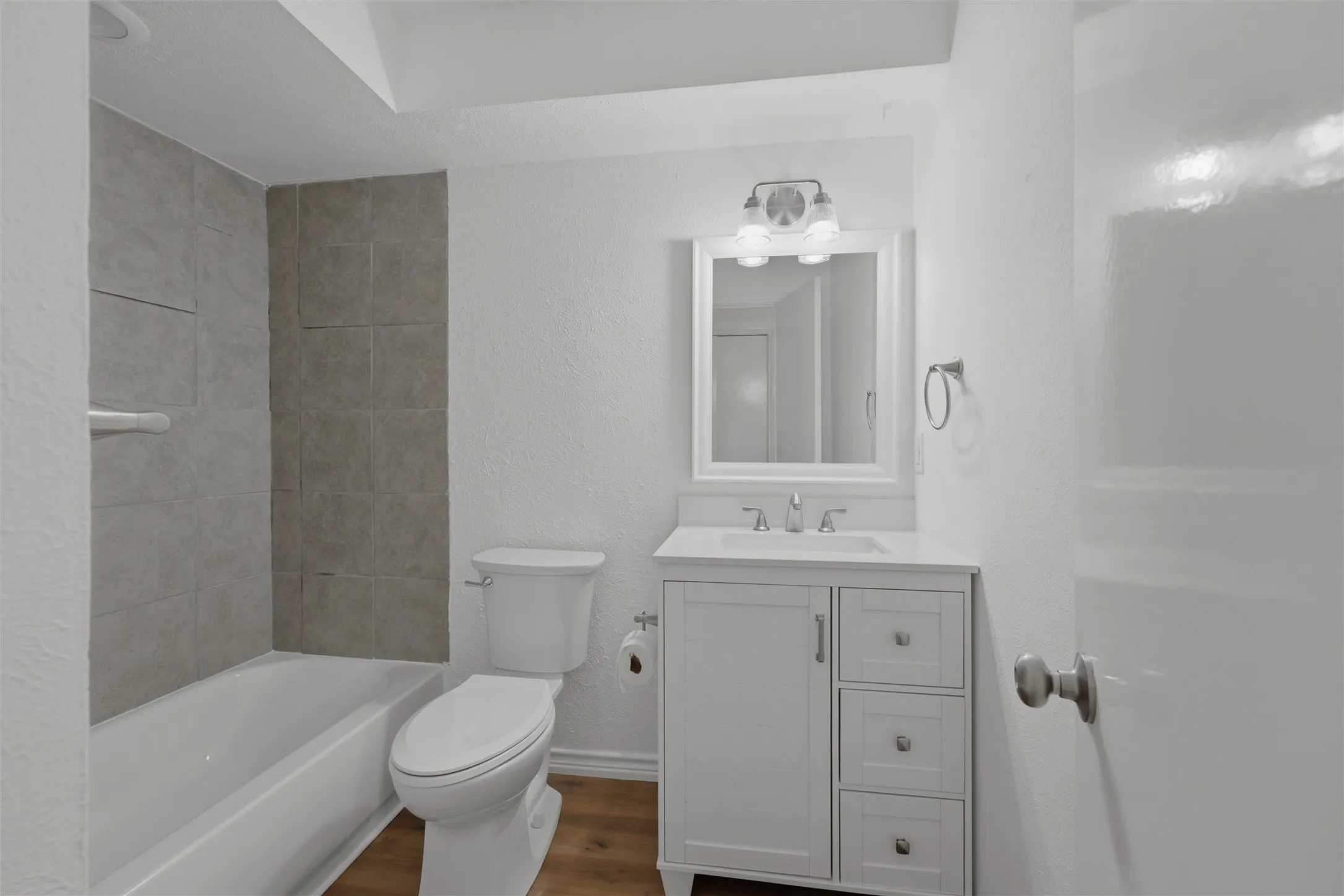 White vanity with a single sink, chrome faucet, and framed mirror