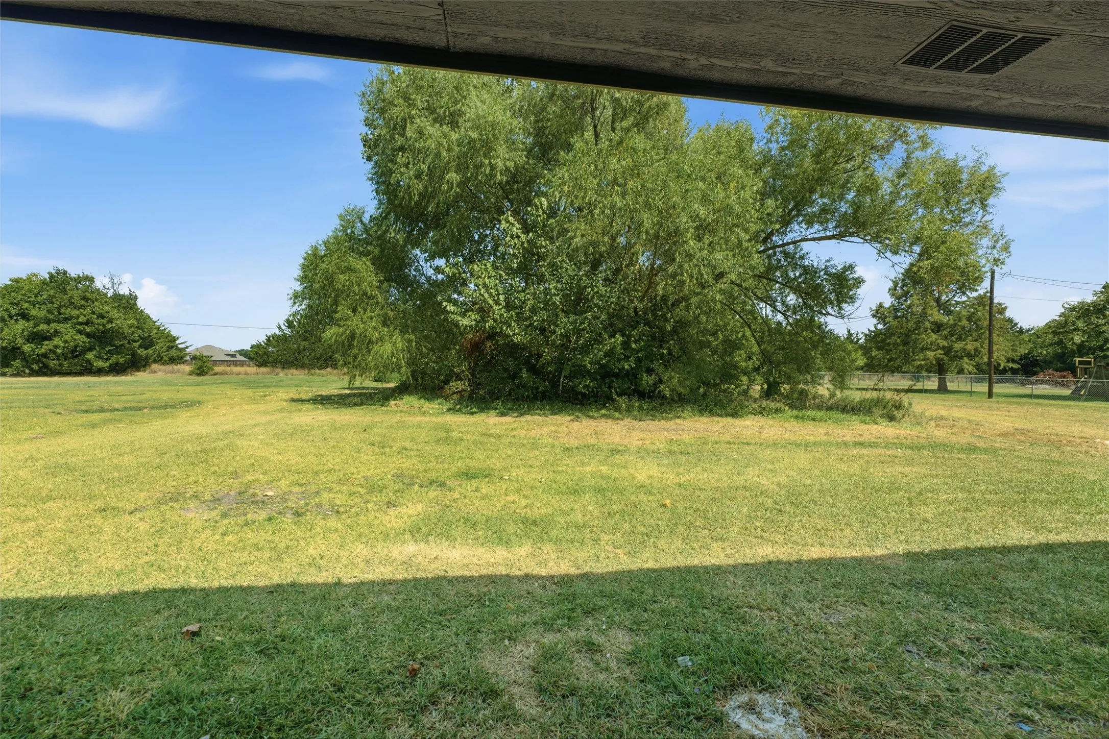 Expansive grassy area with mature trees and open sky