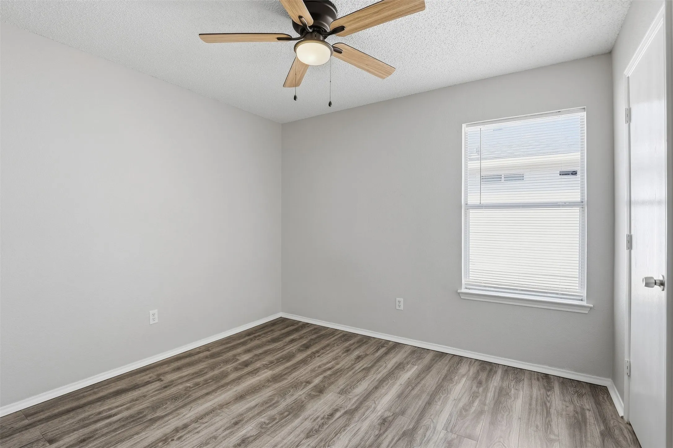 Wood-finish flooring, ceiling fan with integrated lighting, and a window with blinds