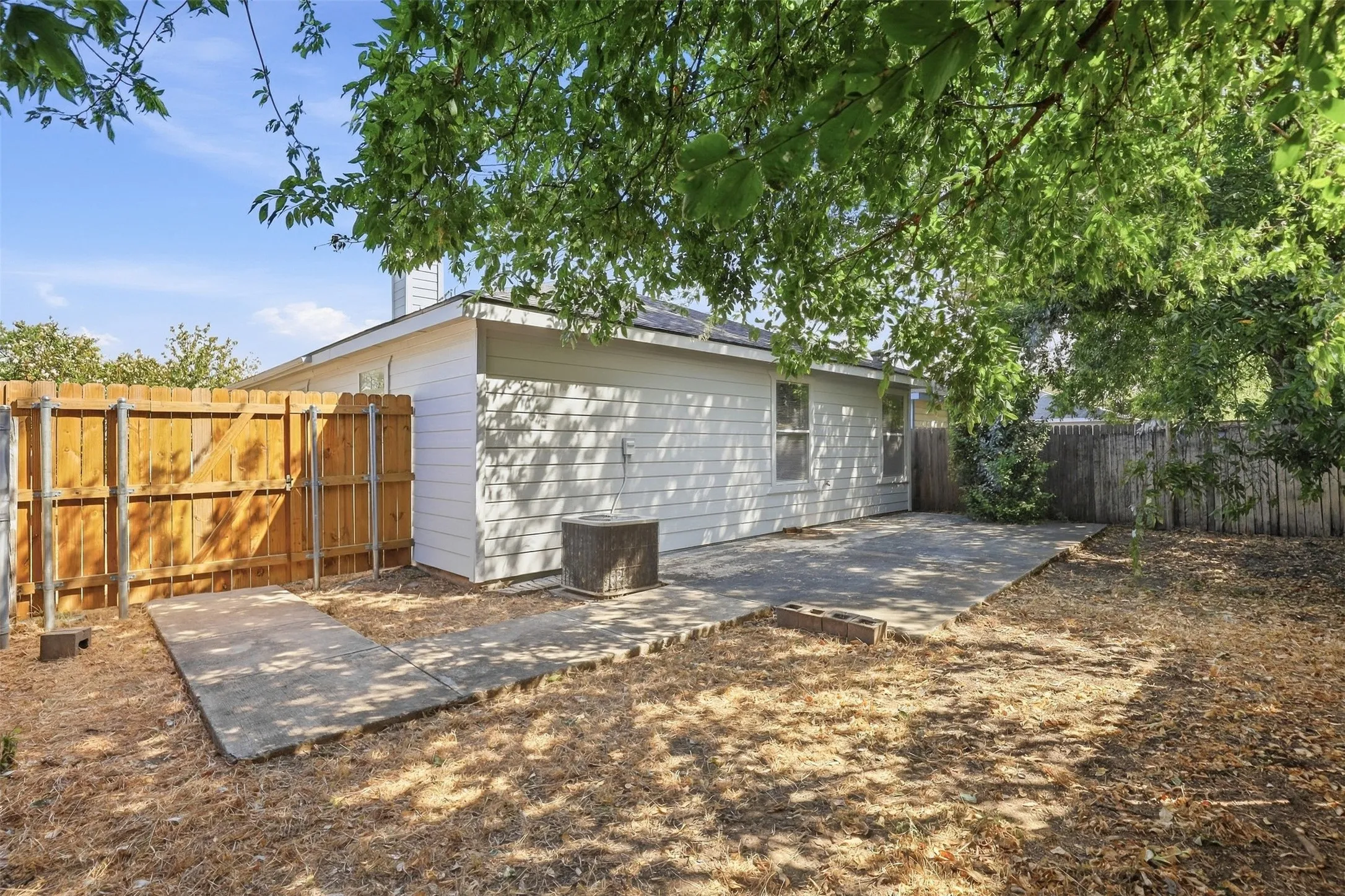 Private backyard with wood fencing, concrete patio, and mature trees