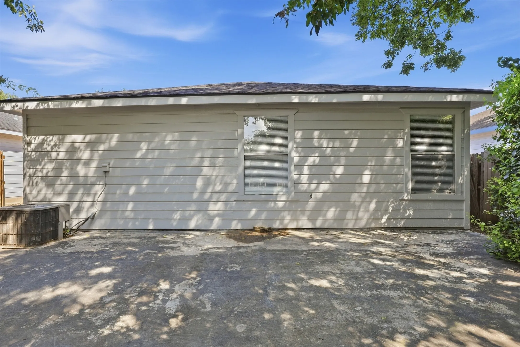 Exterior siding with two windows and a concrete patio
